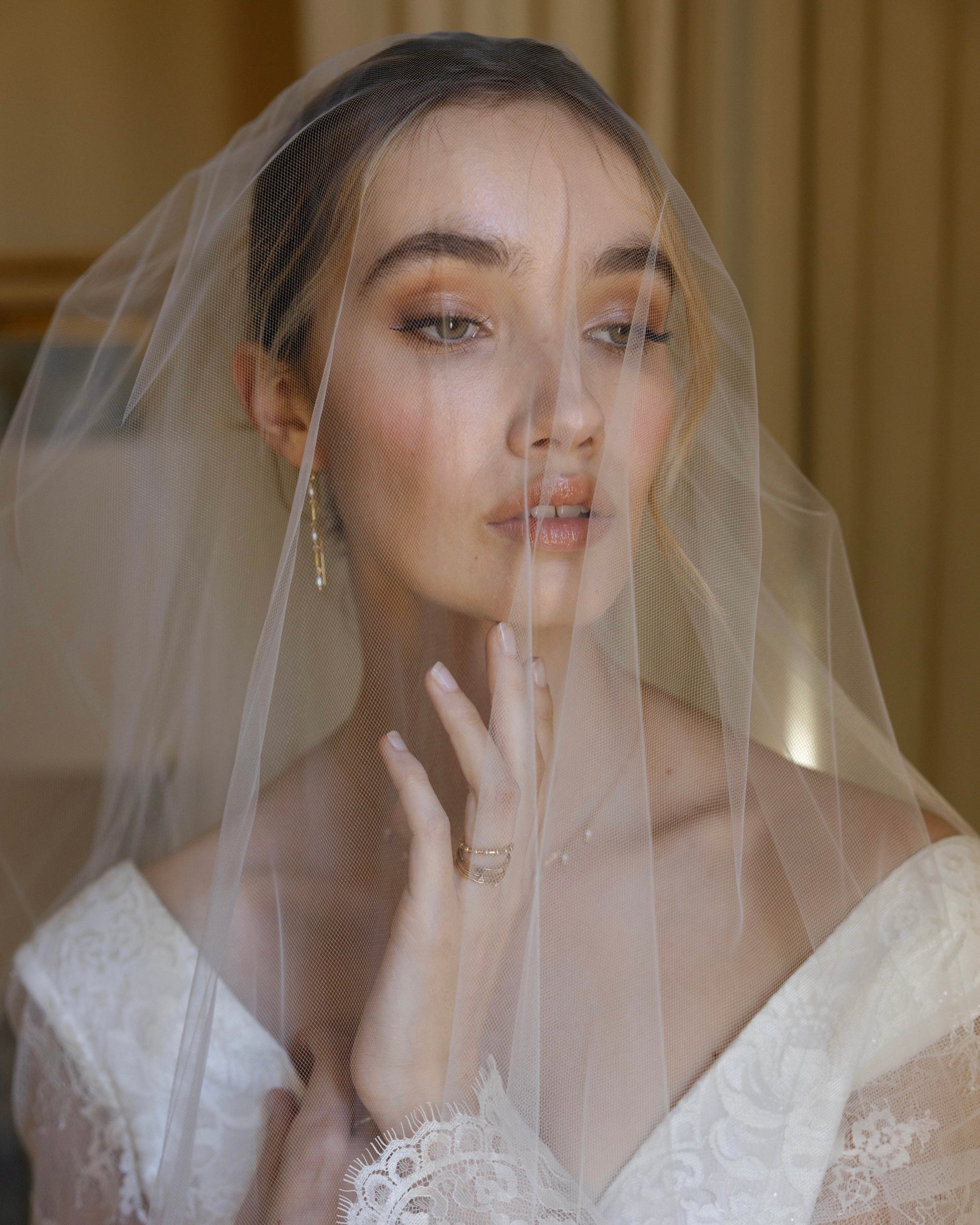 Bride in wedding dress and veil wearing gold and pearl jewellery