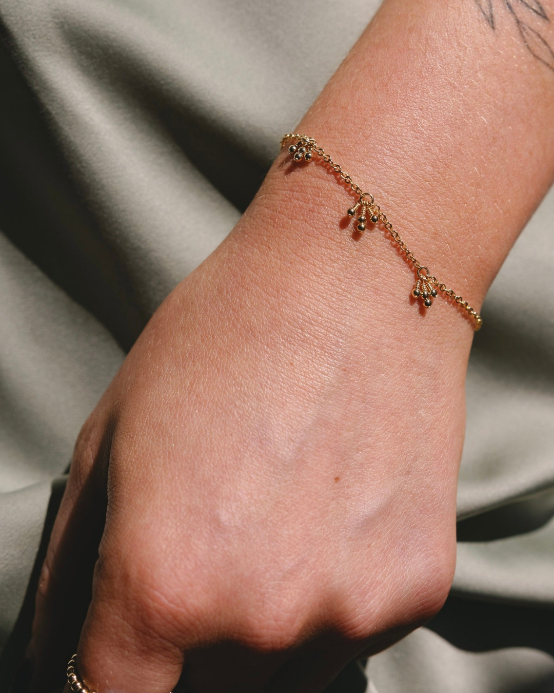 Close-up of a wrist wearing a delicate bracelet on a neutral background