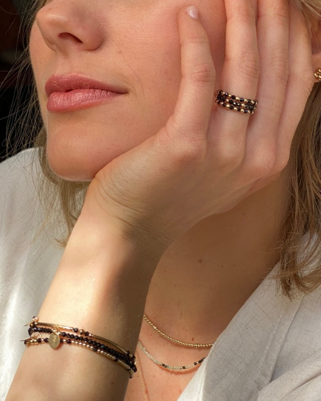 Woman wearing gold and black gemstone beaded rings and bracelets