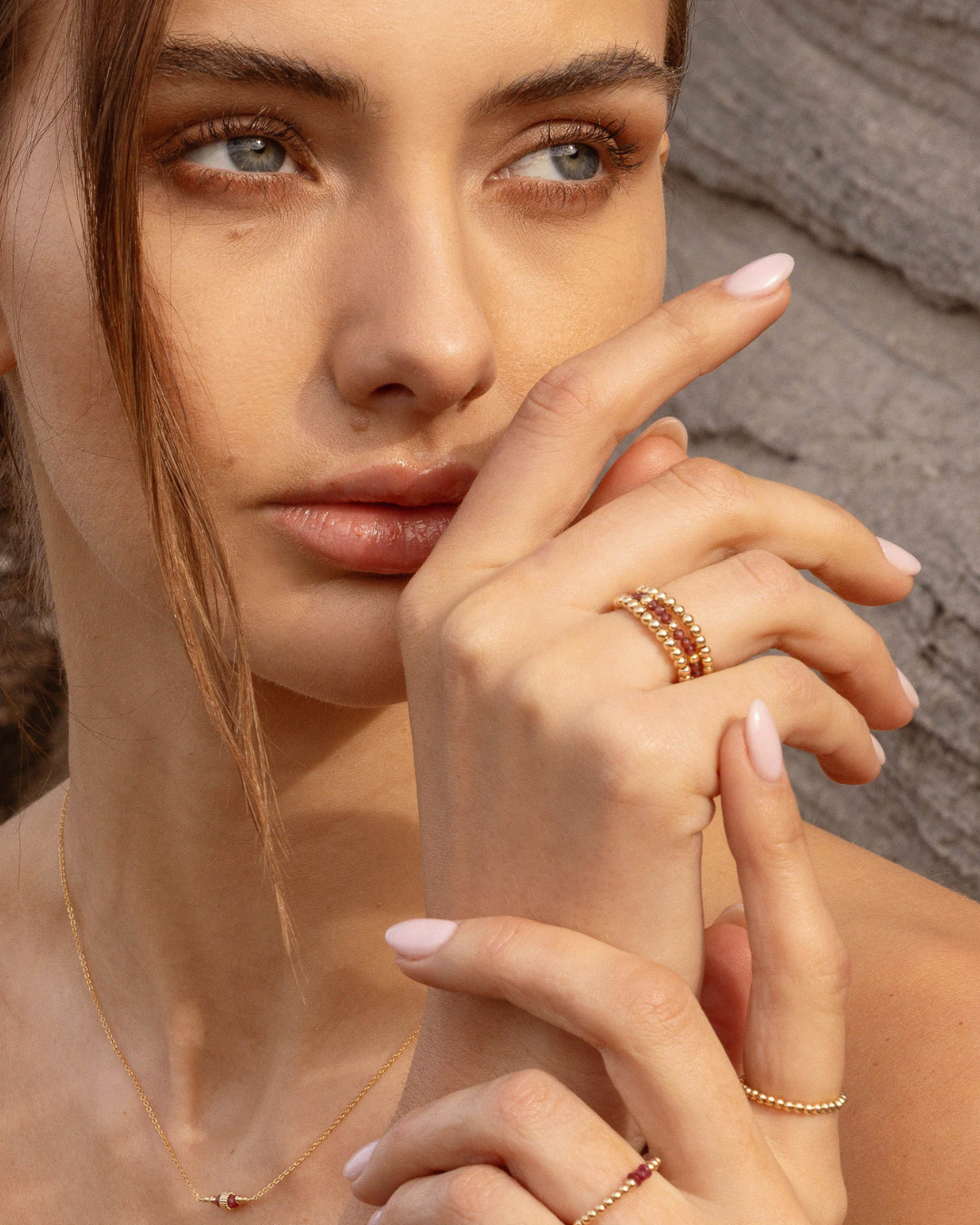 Close-up of a woman's hand with gold rings against a neutral background
