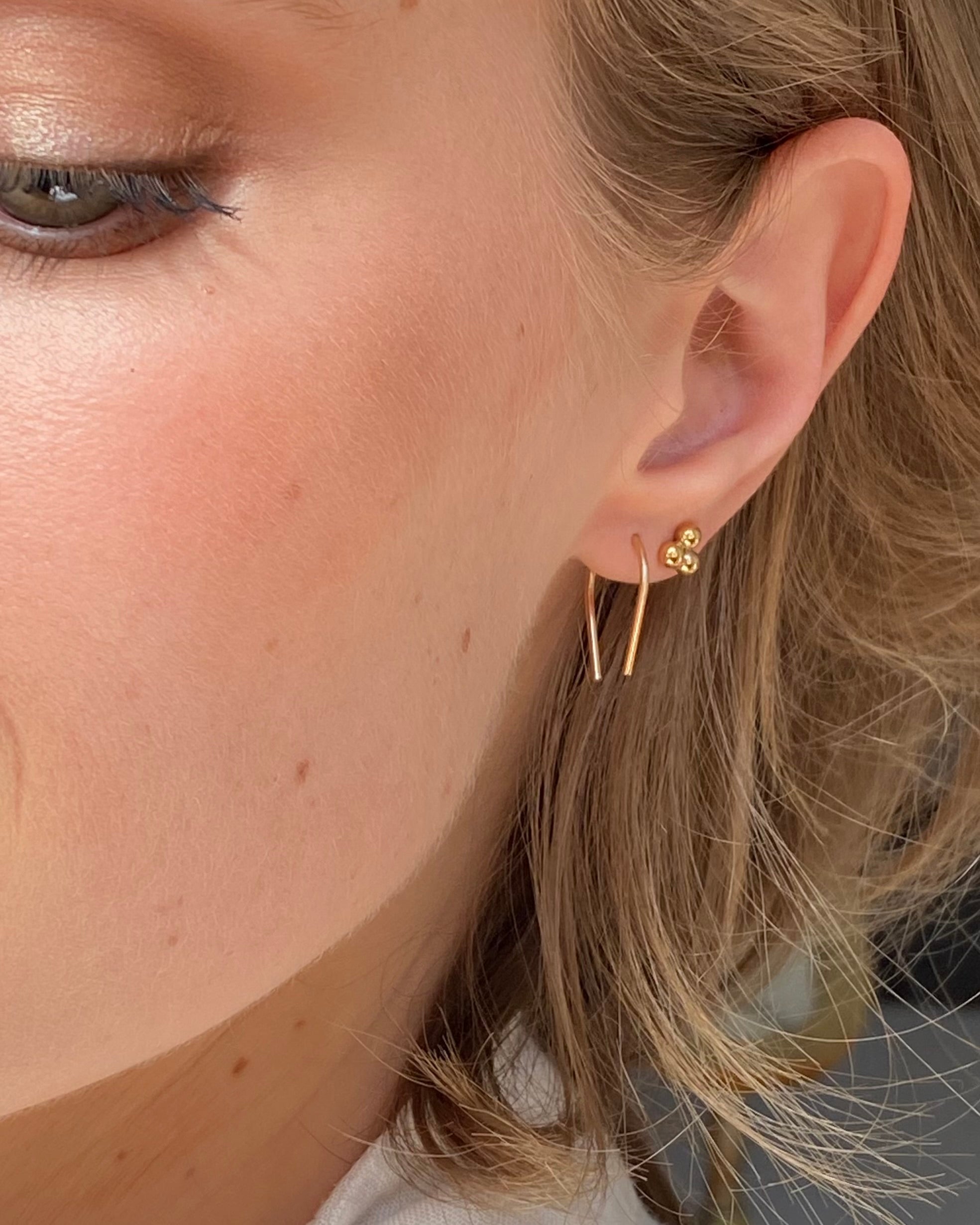 Close-up of a person wearing gold earrings with a blurred background
