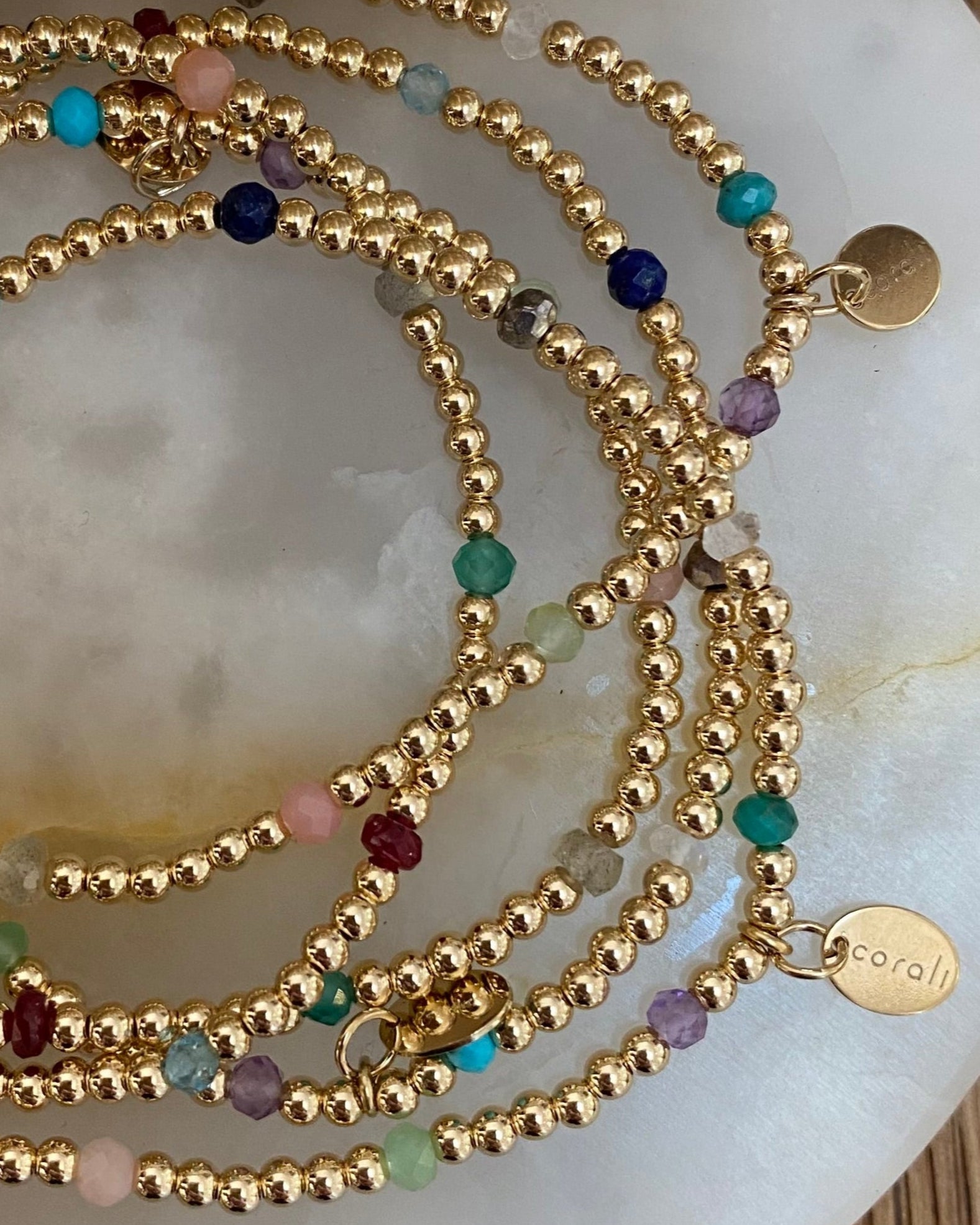 Gold beaded necklace with multicolored beads on a white shell