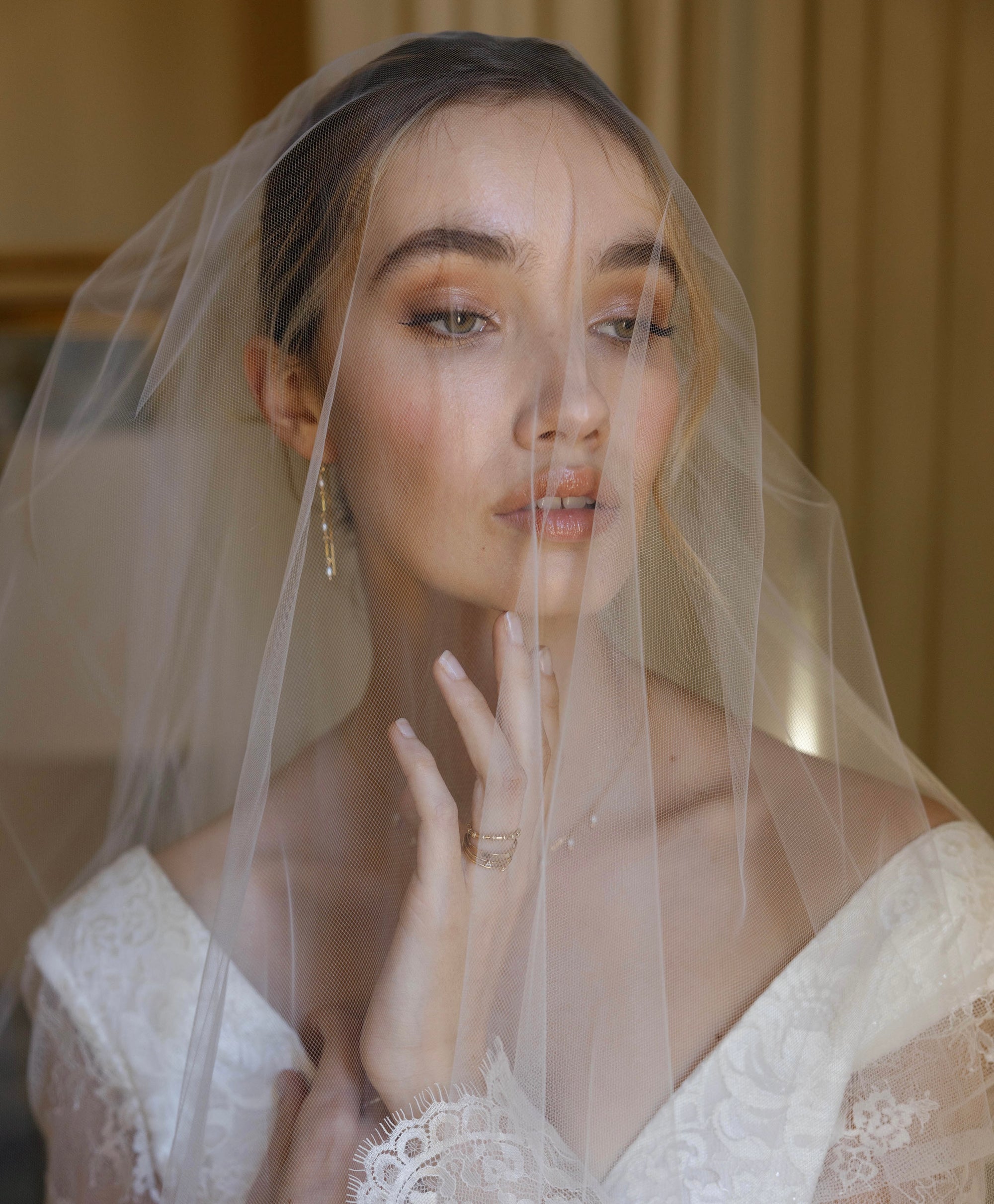 Bride in wedding dress and veil wearing gold and pearl jewellery