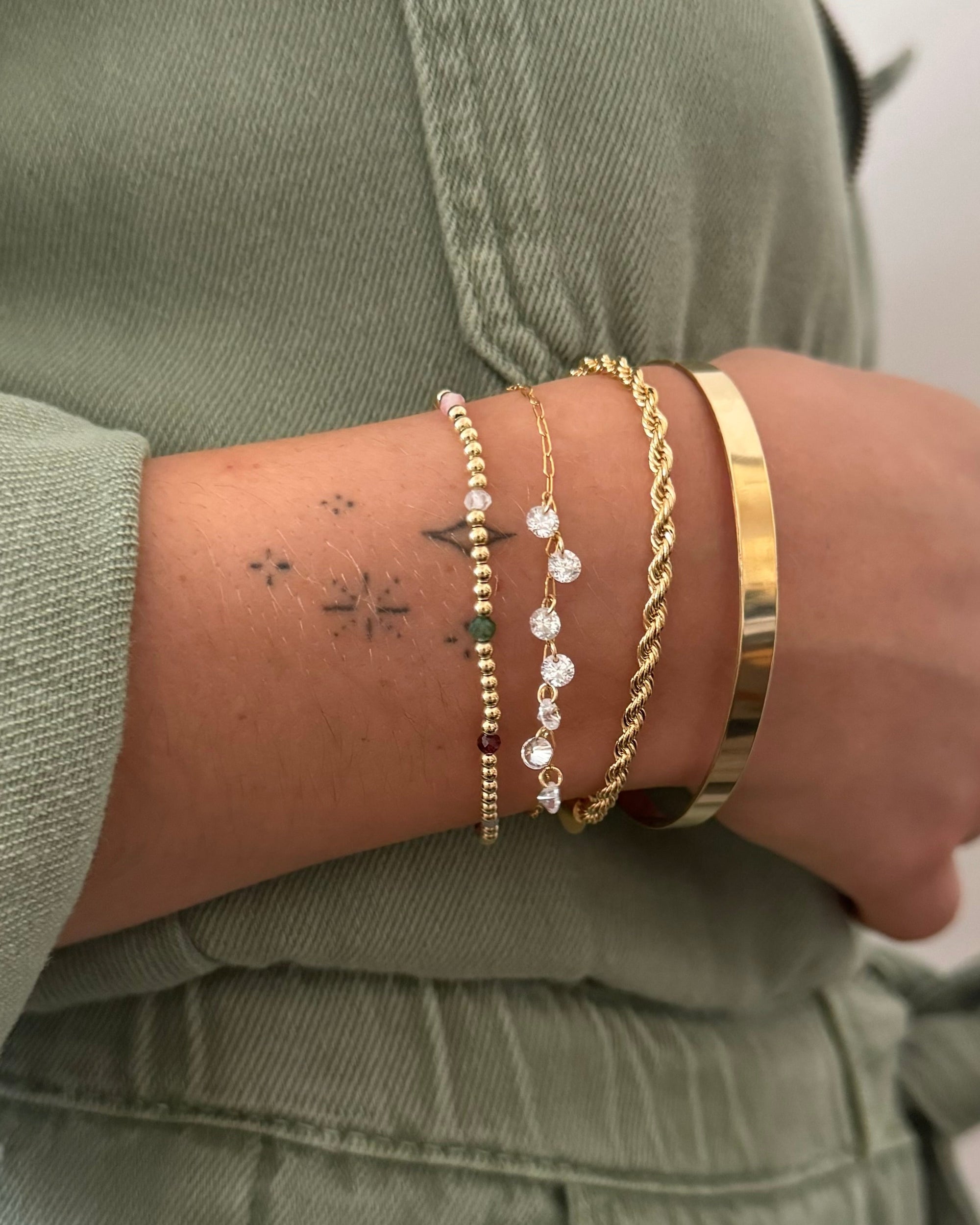 Gold bracelets on a wrist with a neutral background