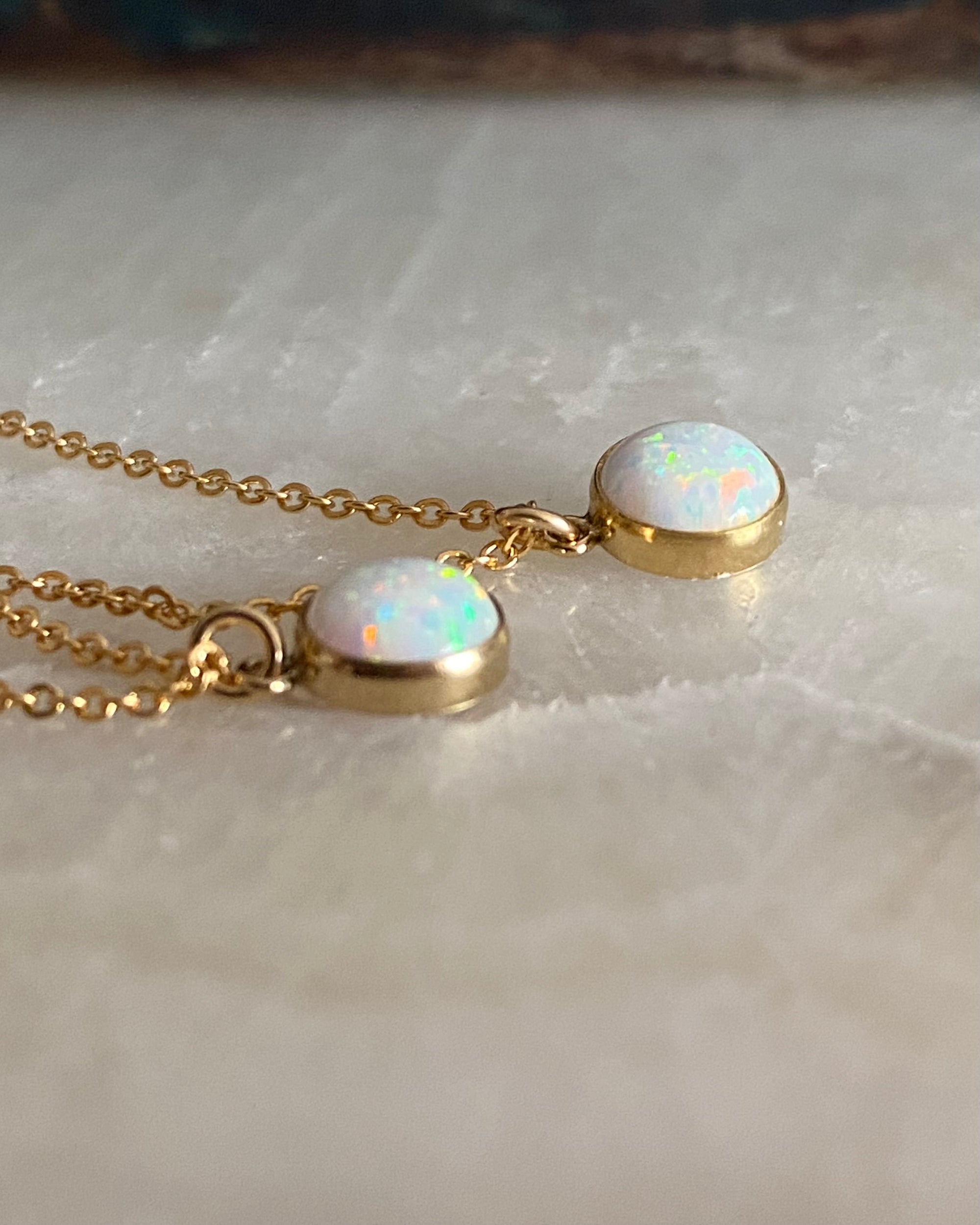 Gold necklace with opal stones on a marble surface