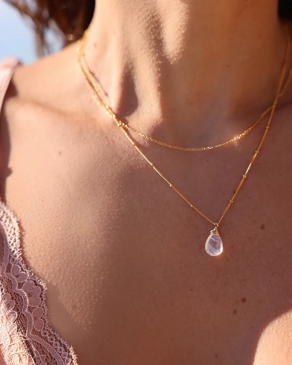 Model wearing necklace featuring a faceted Moonstone gem, wrapped in fine gold-filled wire and suspended from a delicate ball chain
