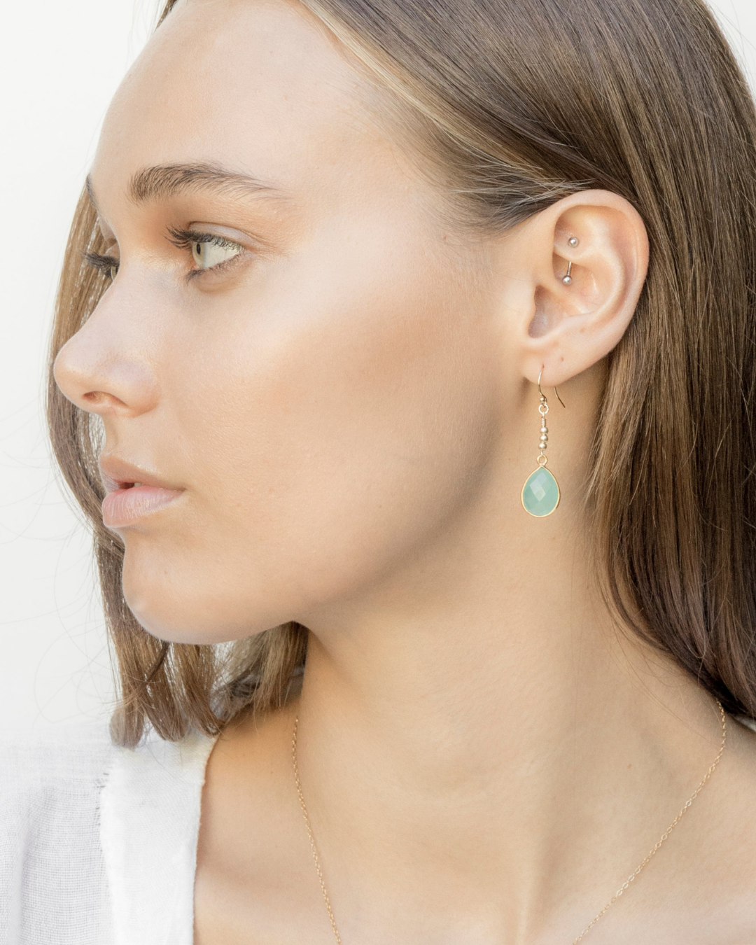 Close-up of a female model wearing gold earrings with chalcedony stones