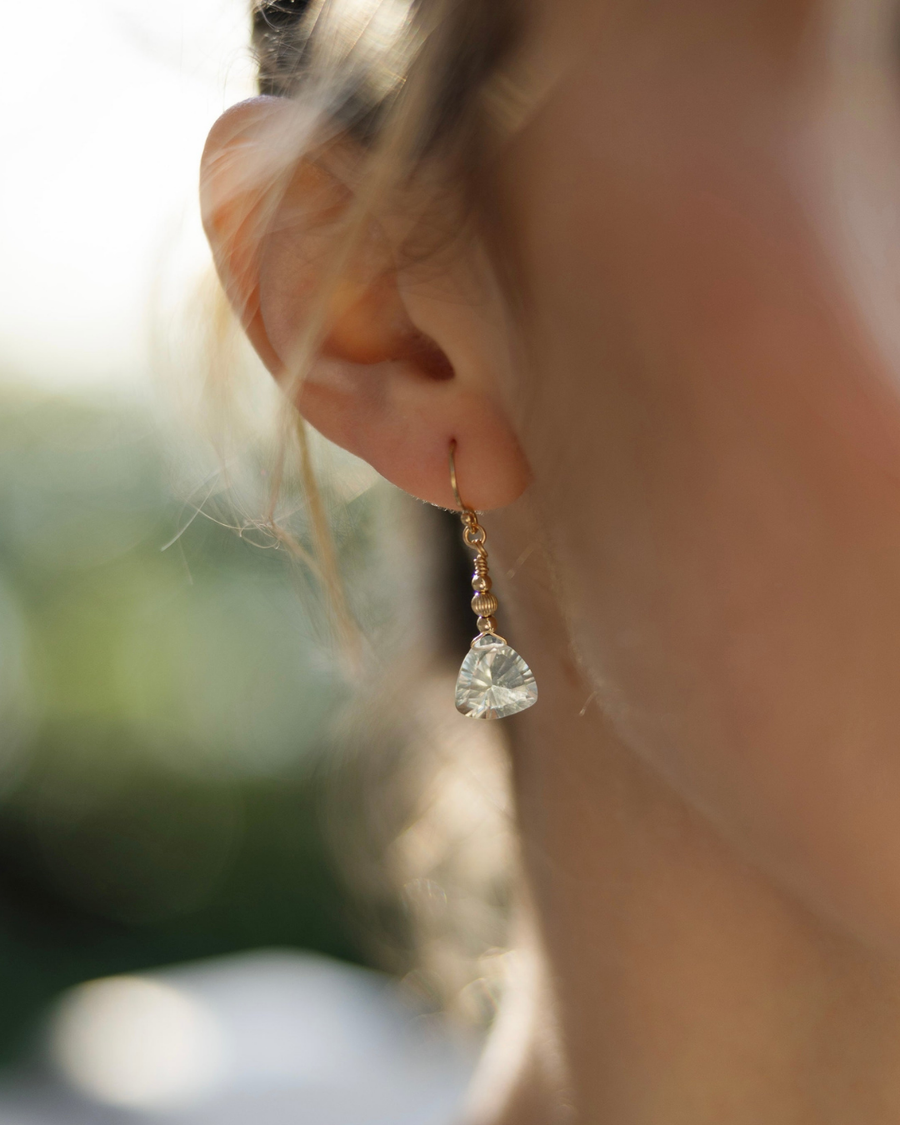 Close-up of earrings with green amethyst  drops worn by a female model with a blurred background