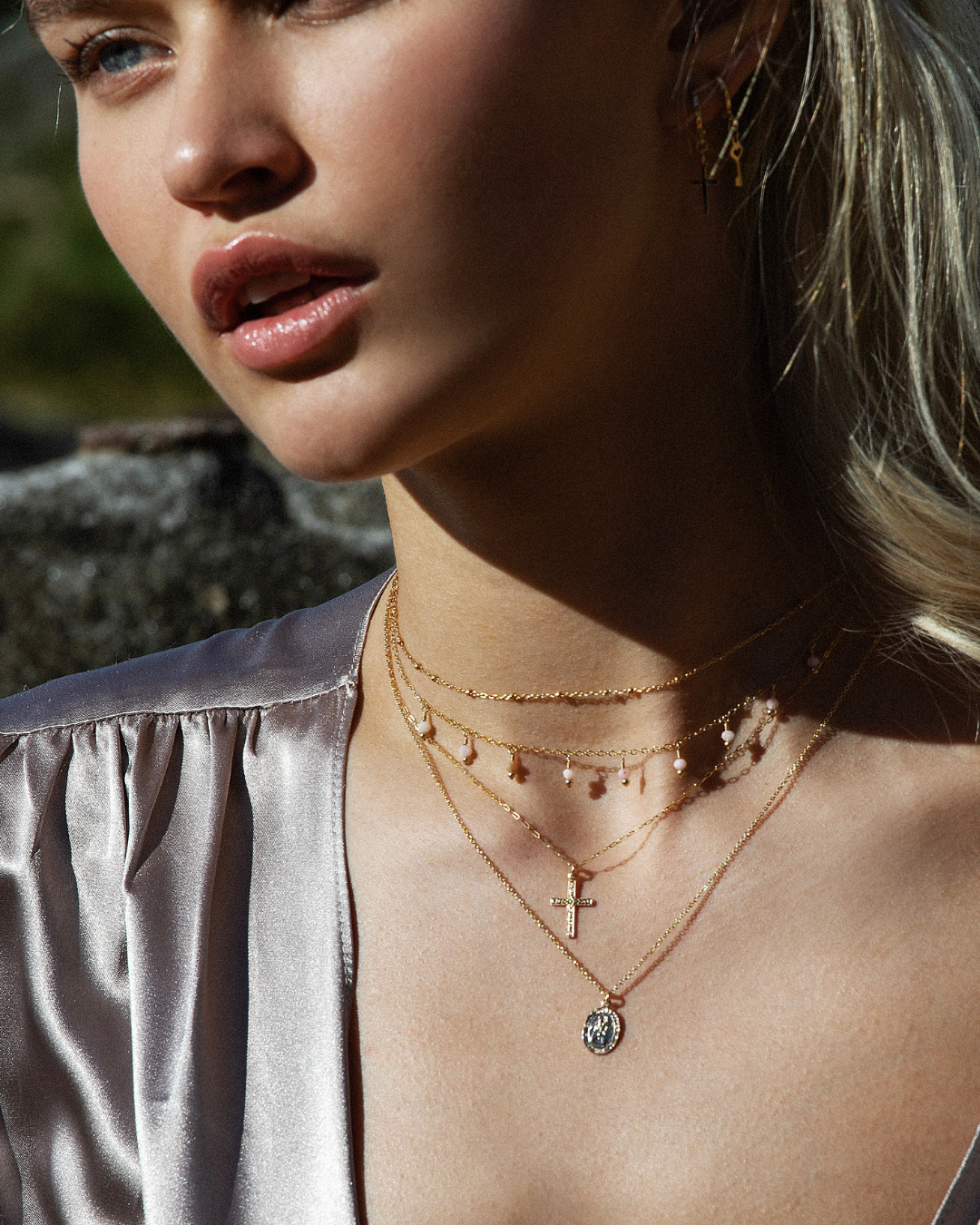 Close-up of a woman wearing gold layered necklaces with a blurred background