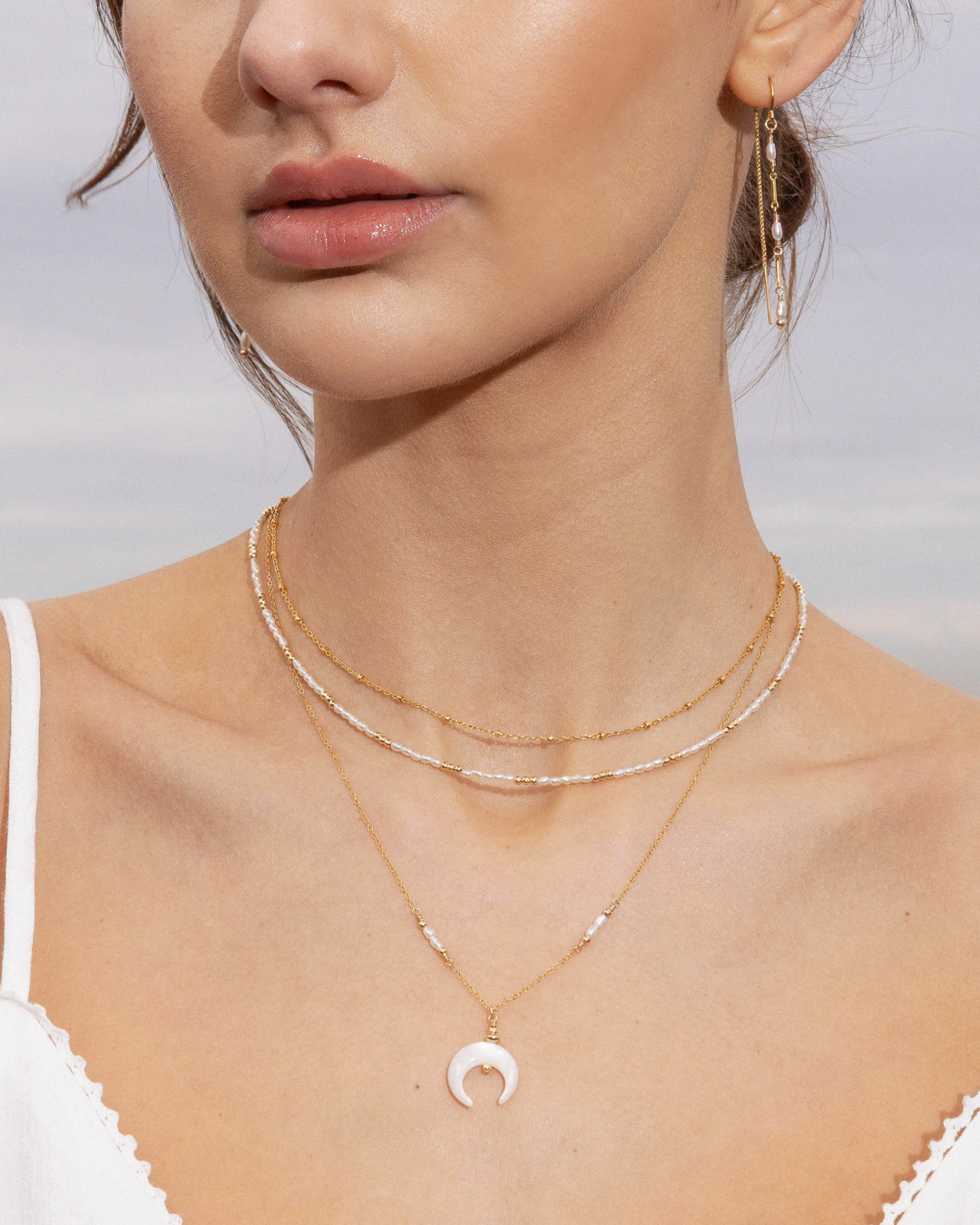 Close-up of a woman's neck with  gold layered necklaces.
