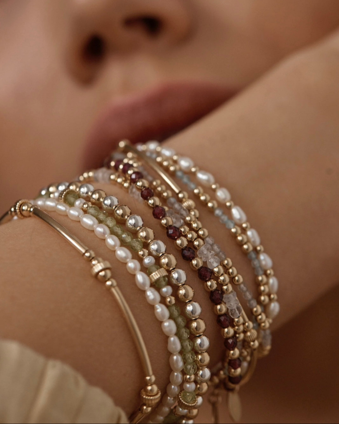 Close-up of a wrist wearing multiple beaded bracelets with a soft focus background