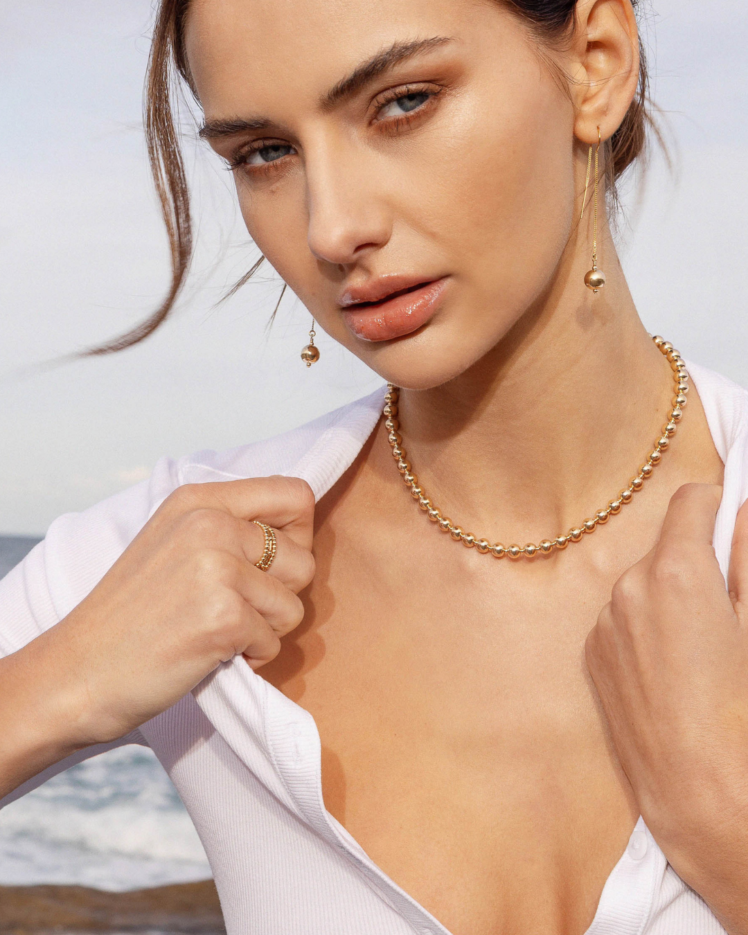 Woman wearing gold jewelry with a blurred background