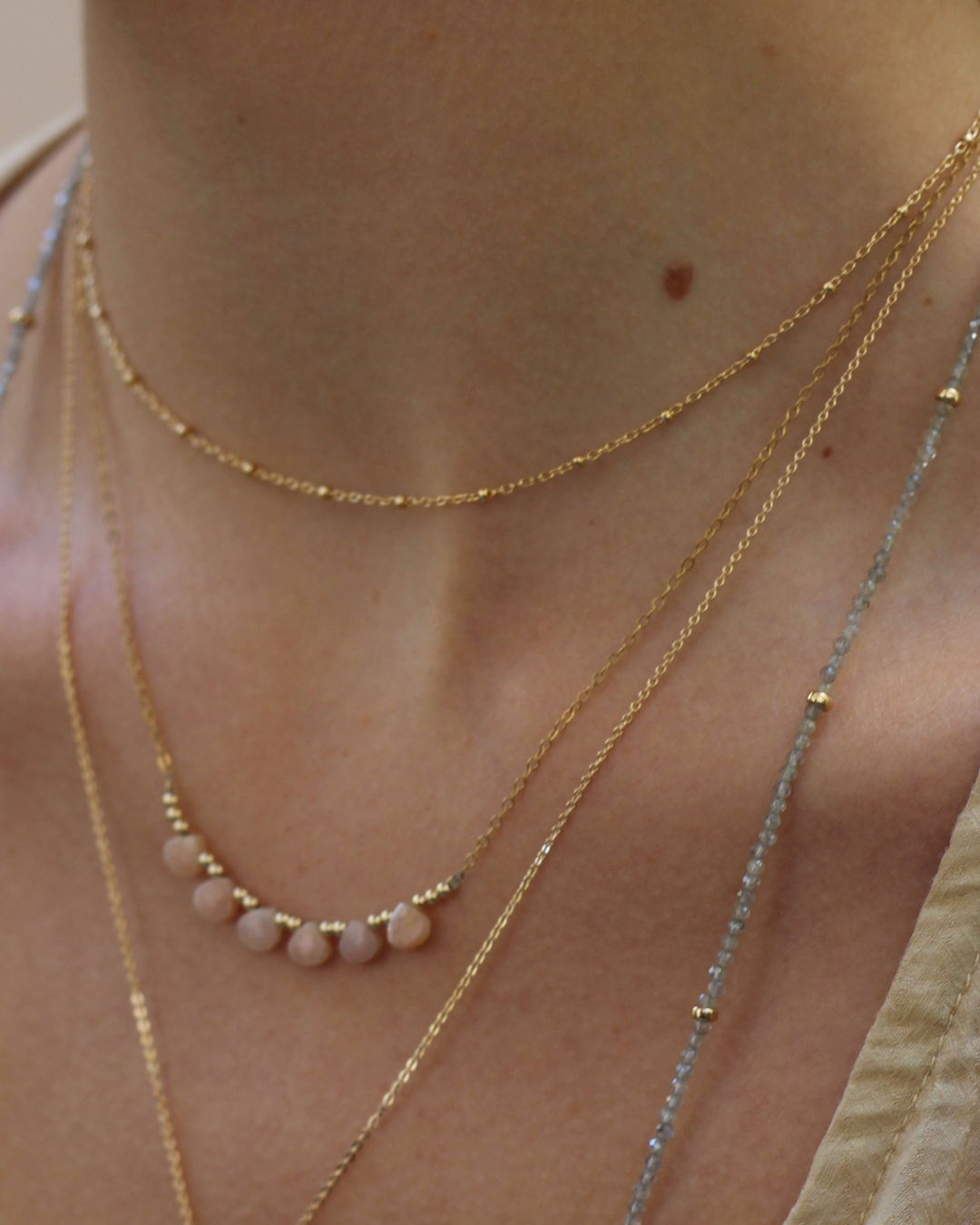 Close-up of a person wearing multiple gold necklaces with beads.