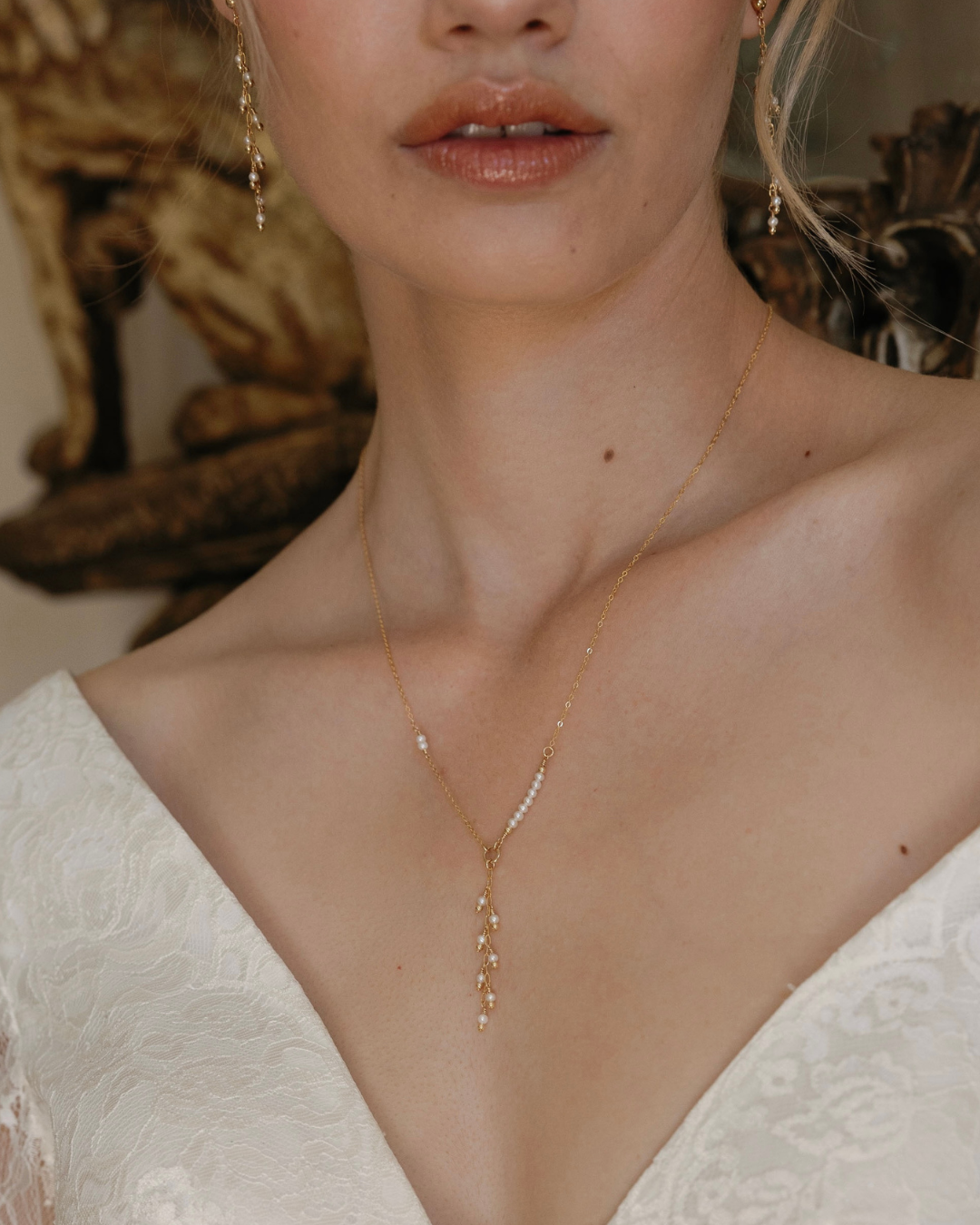 Close-up of a bride wearing a delicate gold and pearl necklace.