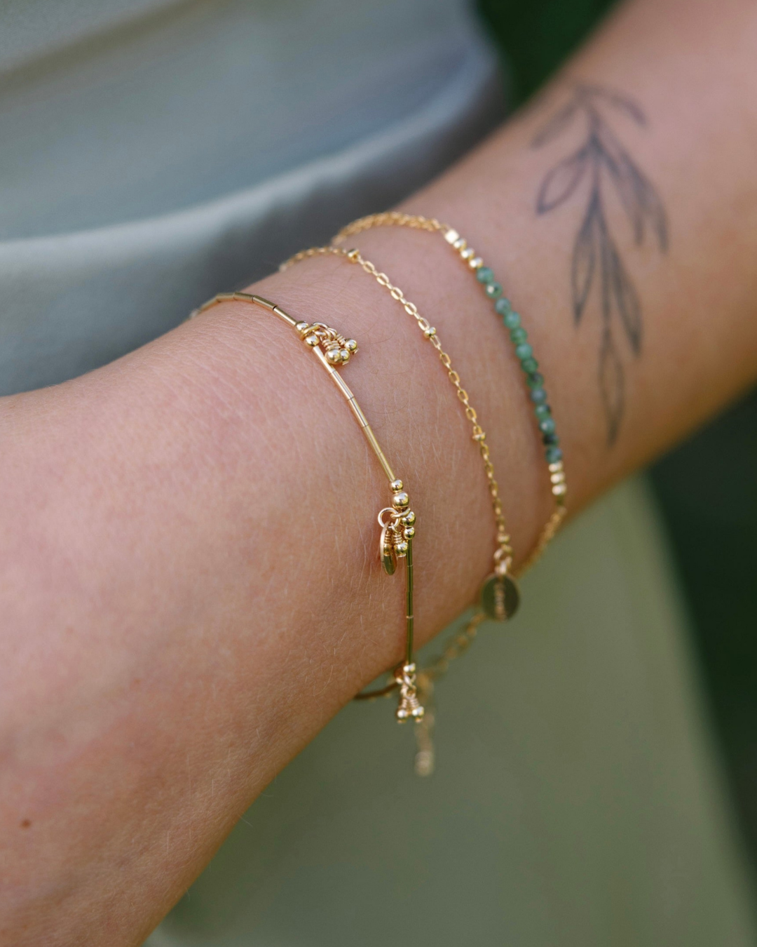 Gold bracelets on a wrist with a blurred background