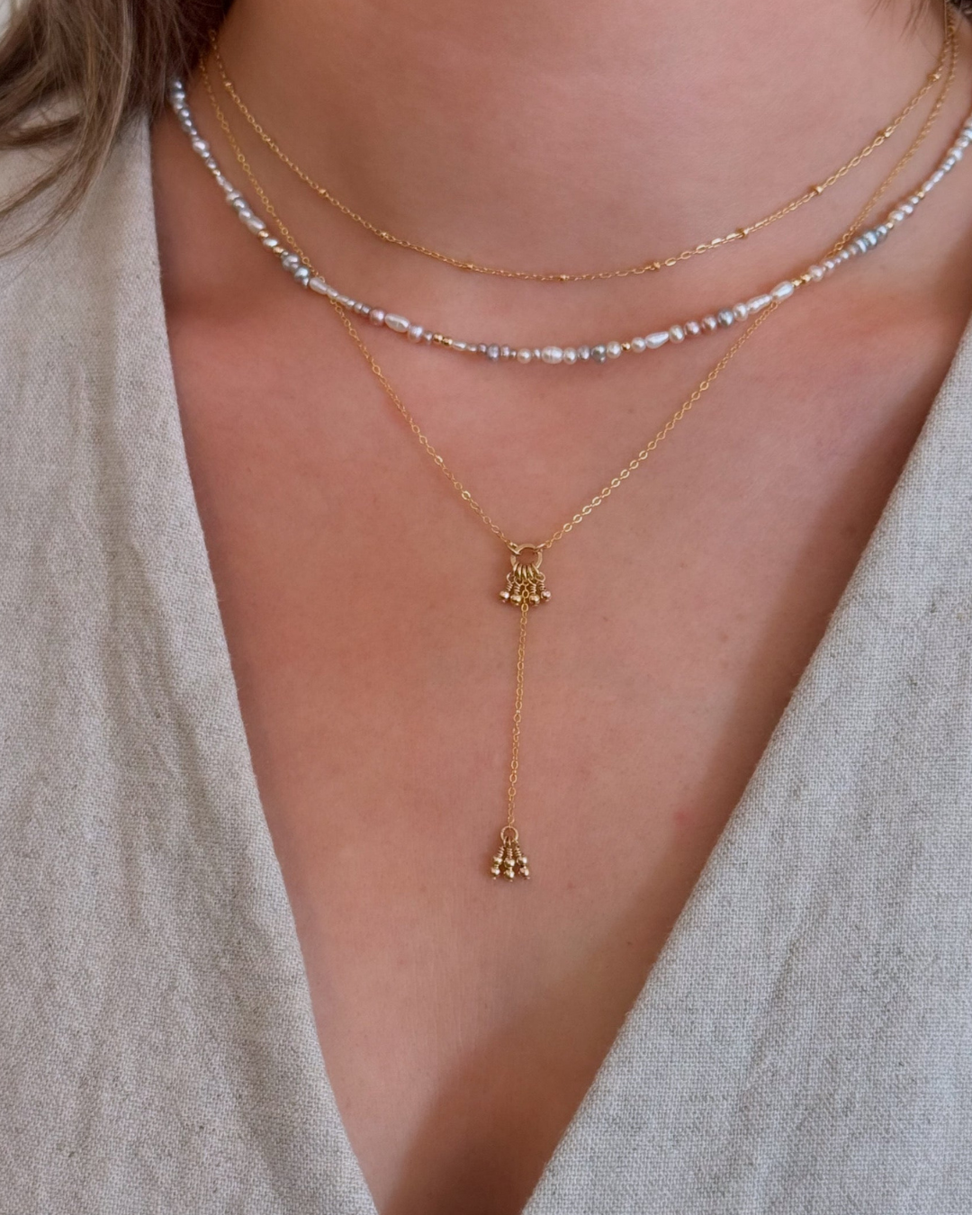 Close-up of layered necklaces with a focus on gold and pearl chains.