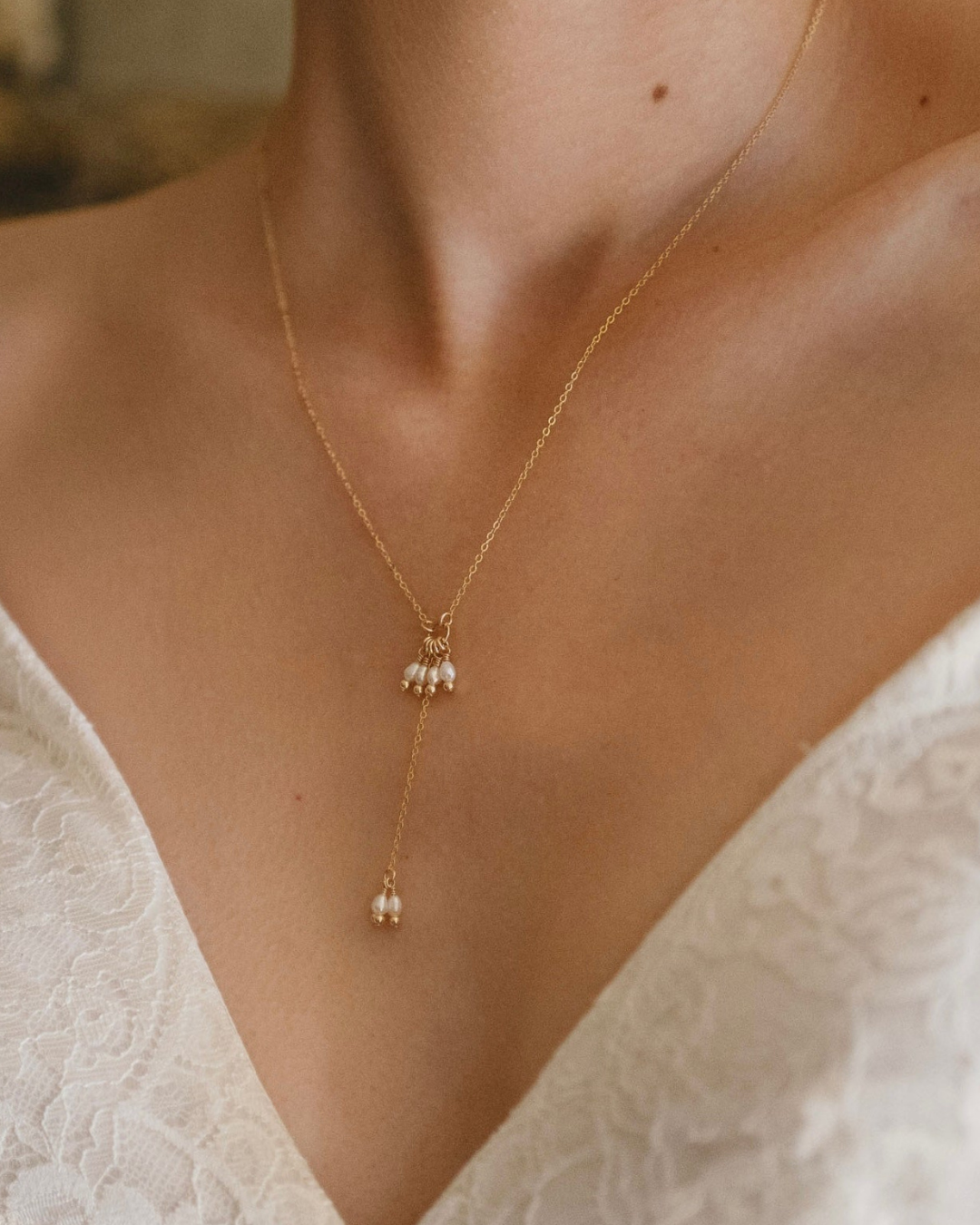 Gold necklace with pearl drops worn by a bride in a wedding dress.