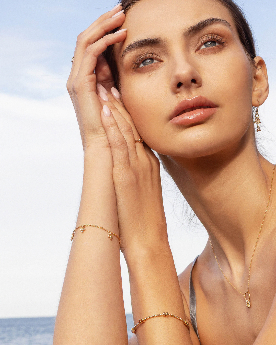 Woman with gold jewelry against a clear sky background