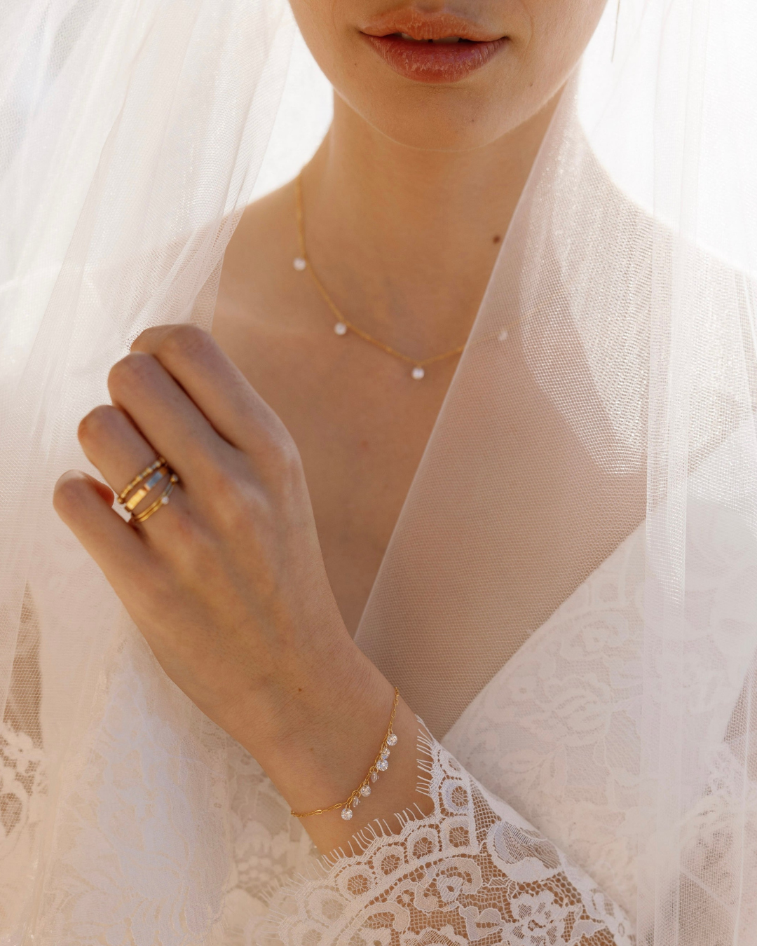 Close-up of a bride in wedding dress and veil wearing gold and Cubic Zirconia jewellery.