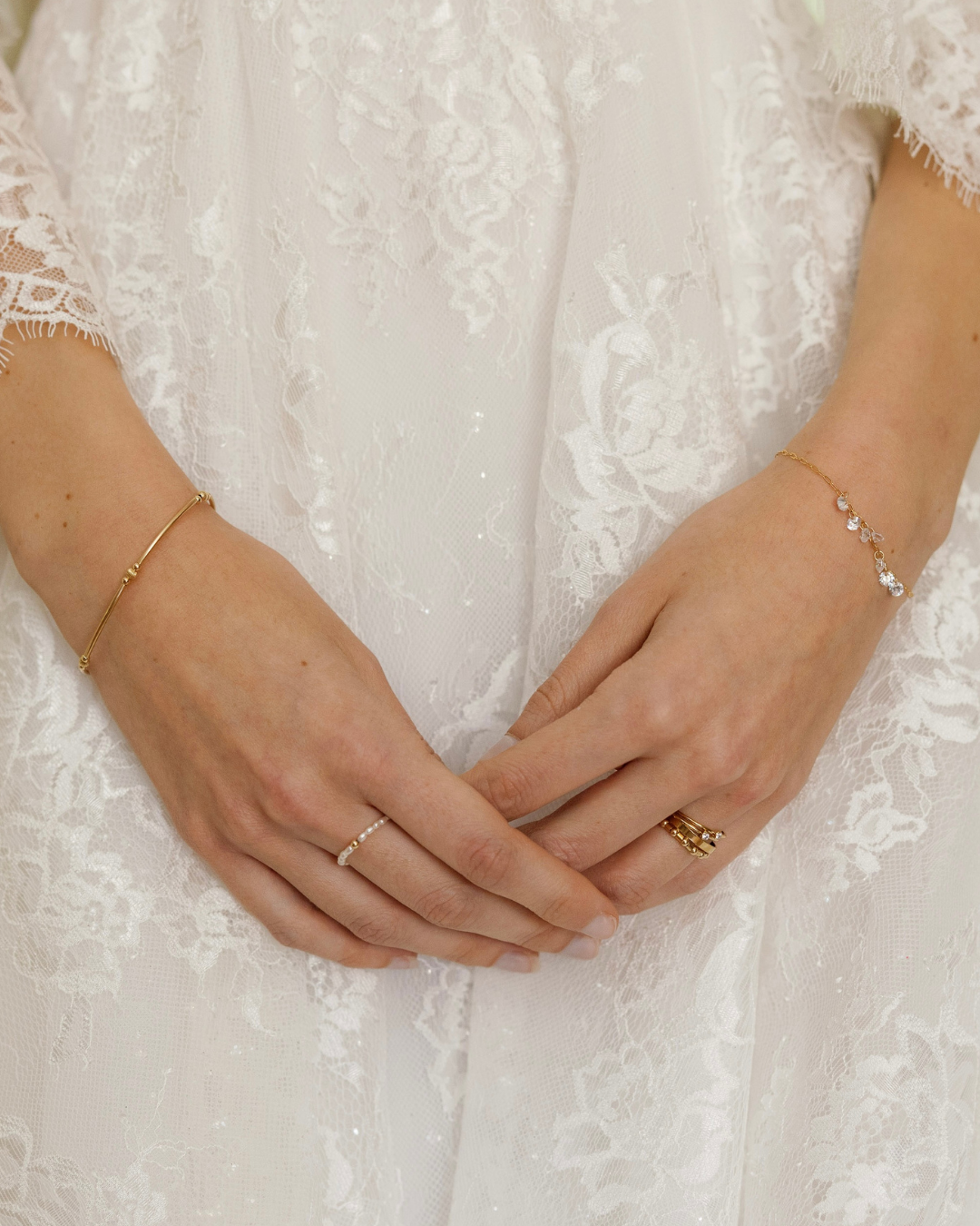Close-up of the hands of a bride in wedding dress with gold and Cubic Zirconia jewllery.