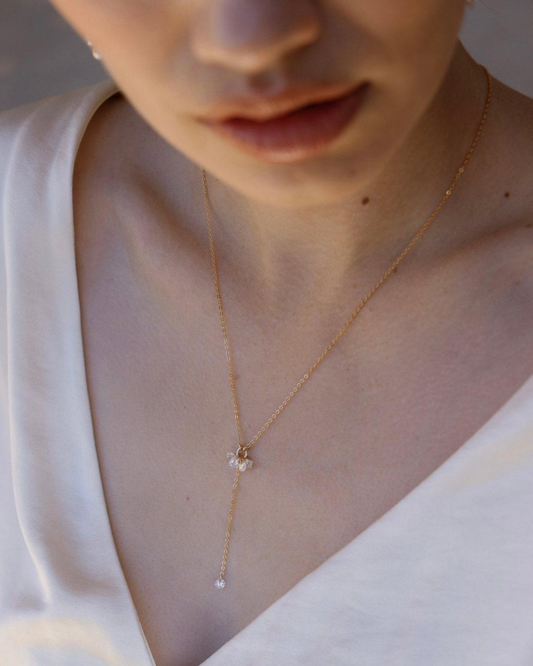 Close-up of a bride's neck with a delicate gold and cubic zirconia necklace.