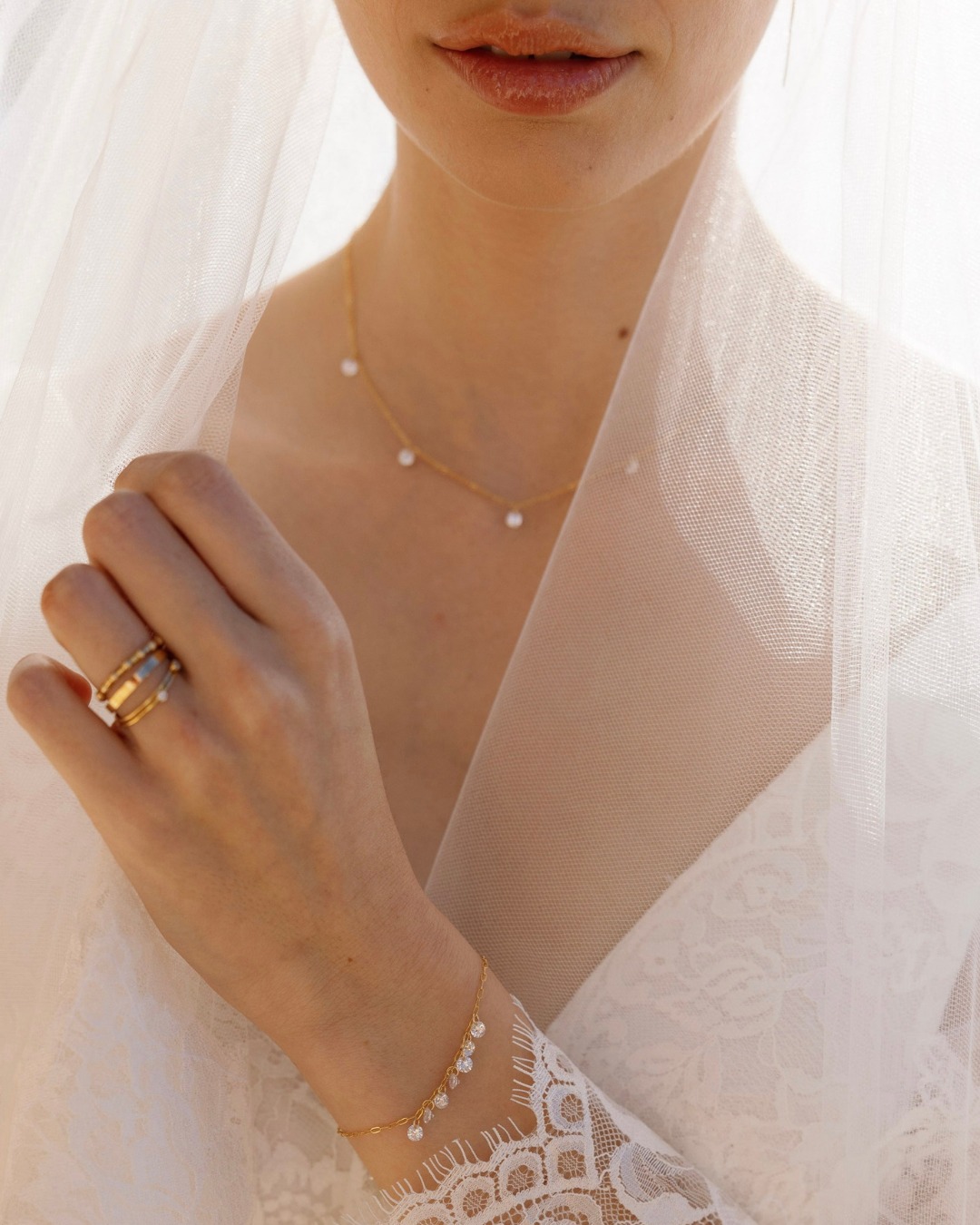 Close-up of a bride in veil wearing gold jewelry with a white fabric background