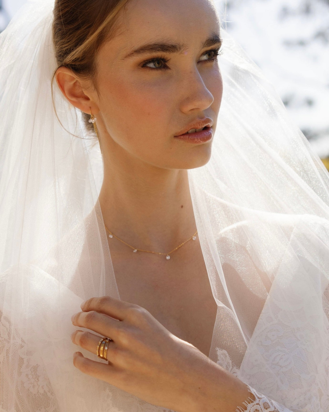 Bride wearing a white veil with a gold and cubic zirconia necklace and earrings.