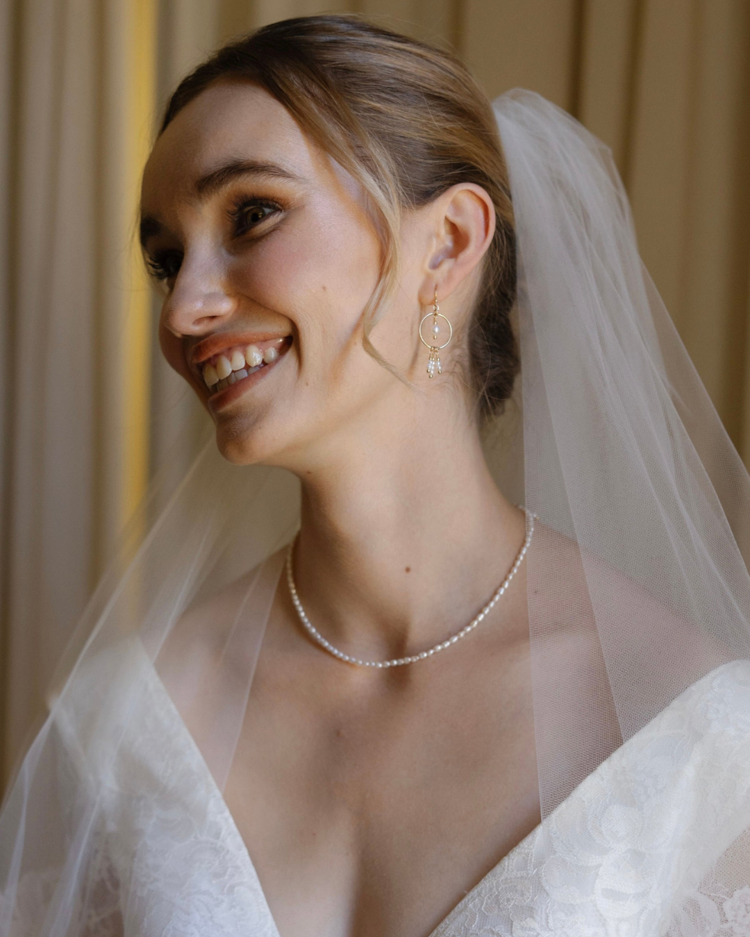 Bride wearing a veil and pearl necklace with a blurred background