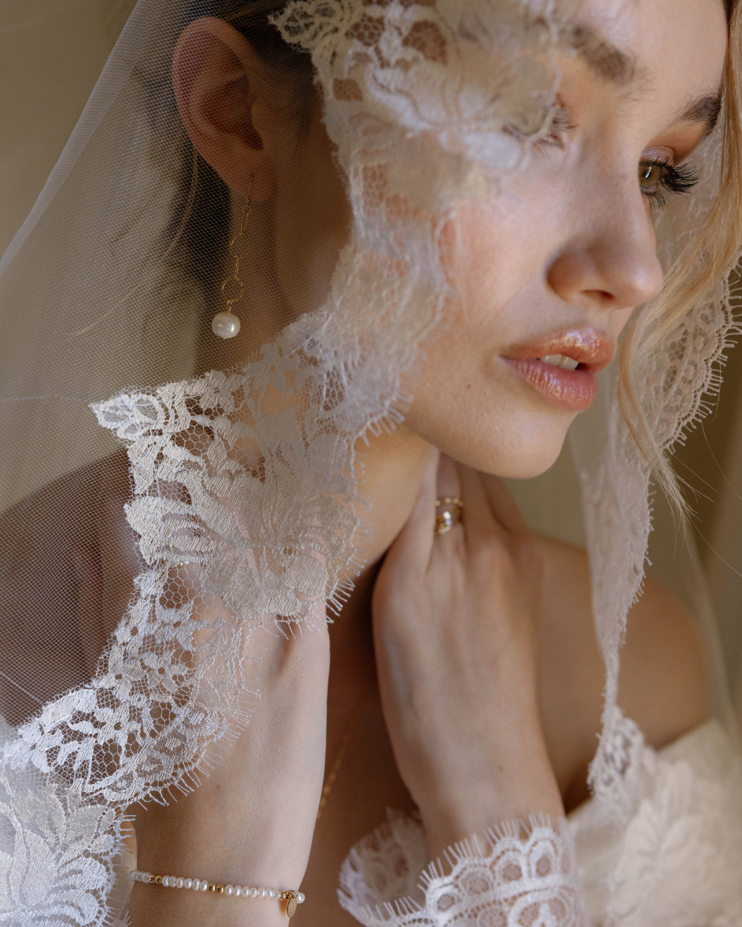 Close-up of a bride wearing a lace veil and earrings.