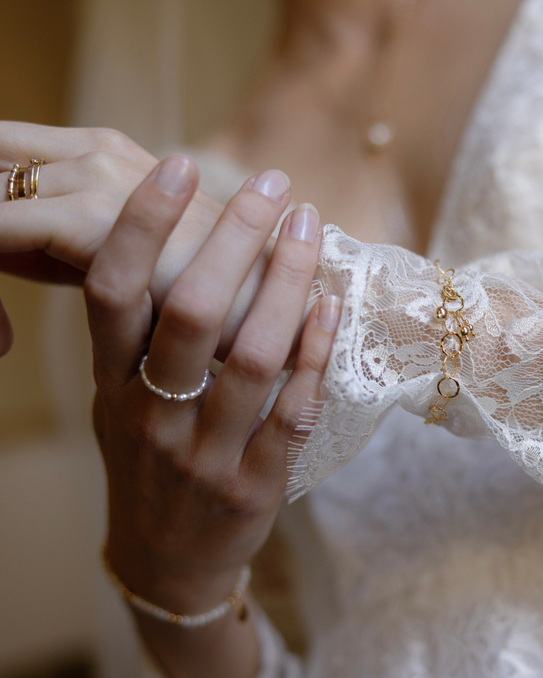 Close-up of a bride's hand wearing multiple rings and bracelet with a blurred background