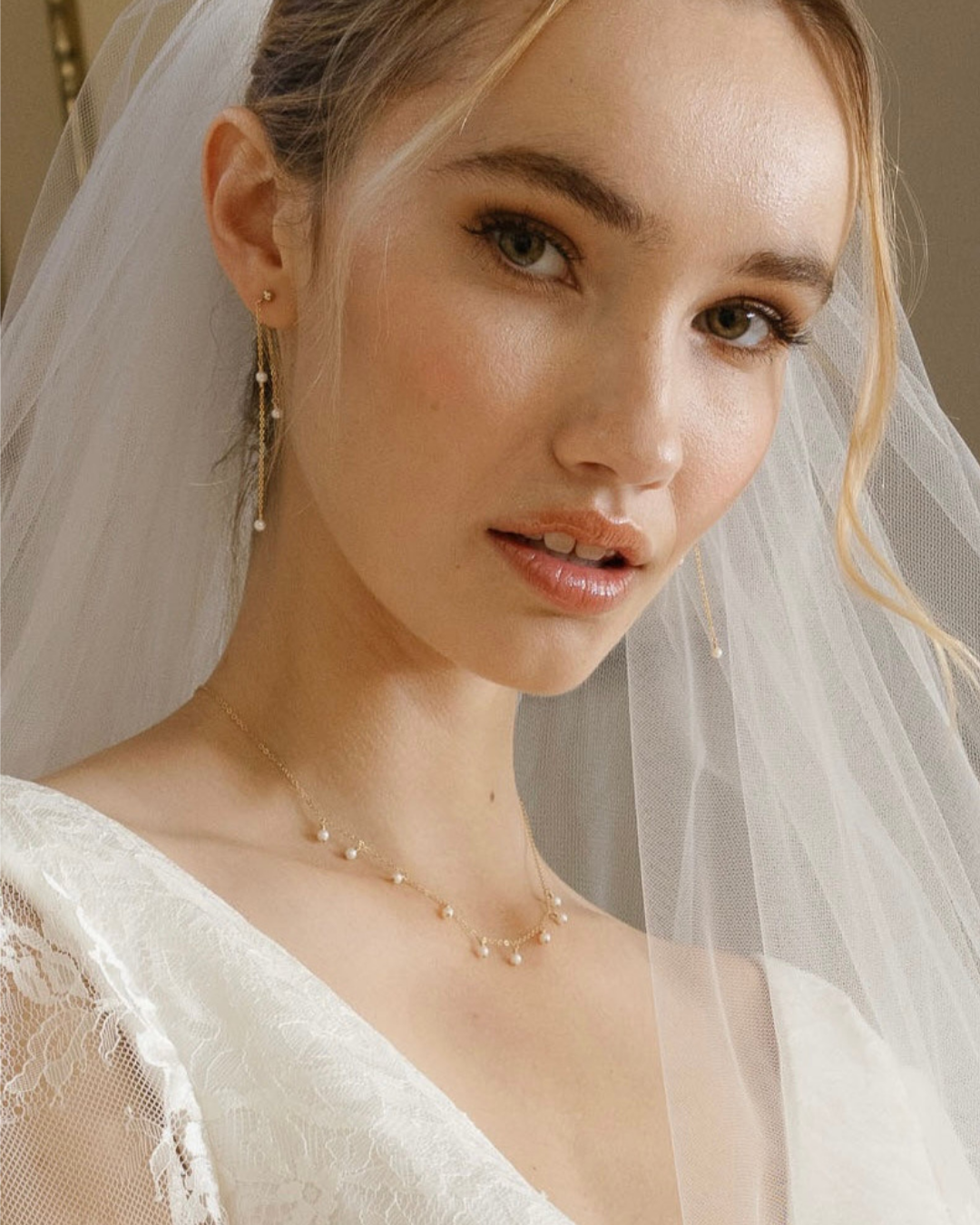 Close-up of a bride wearing a veil and pearl necklace.