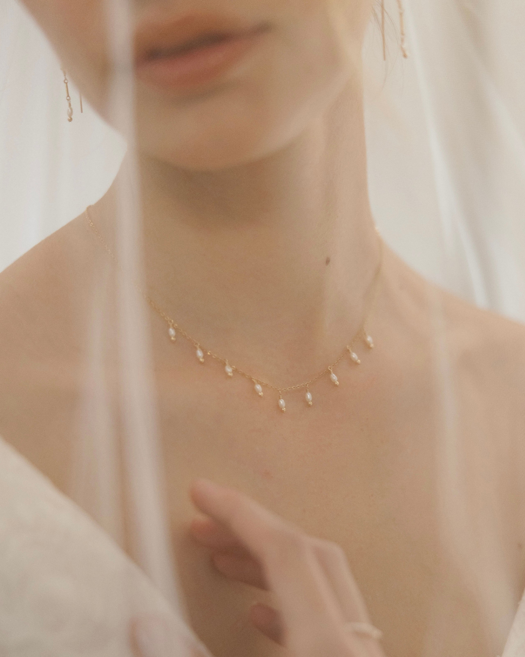 Close-up of a delicate necklace with small pearls on a blurred background
