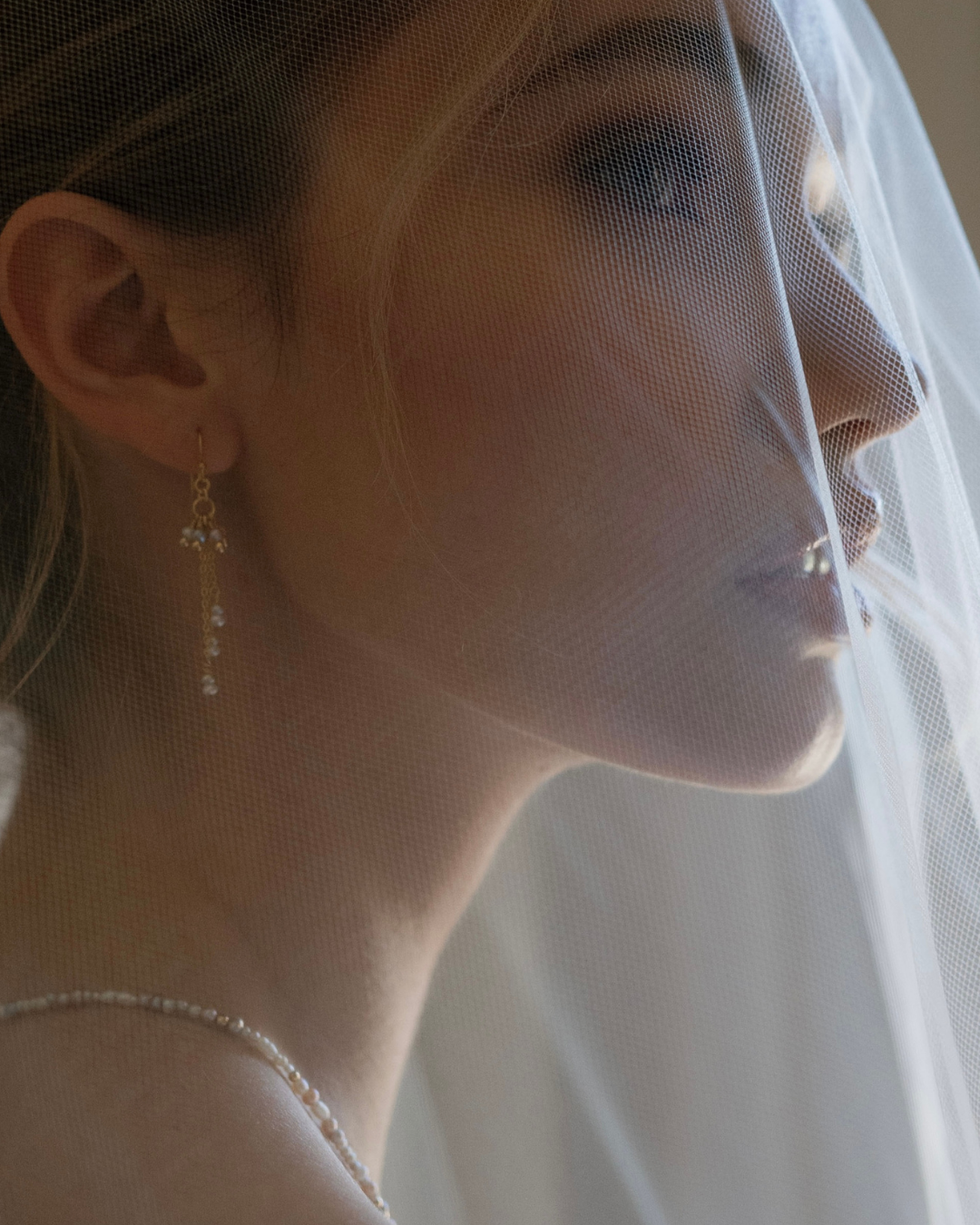 Close-up of a woman wearing a veil and pearl earrings.