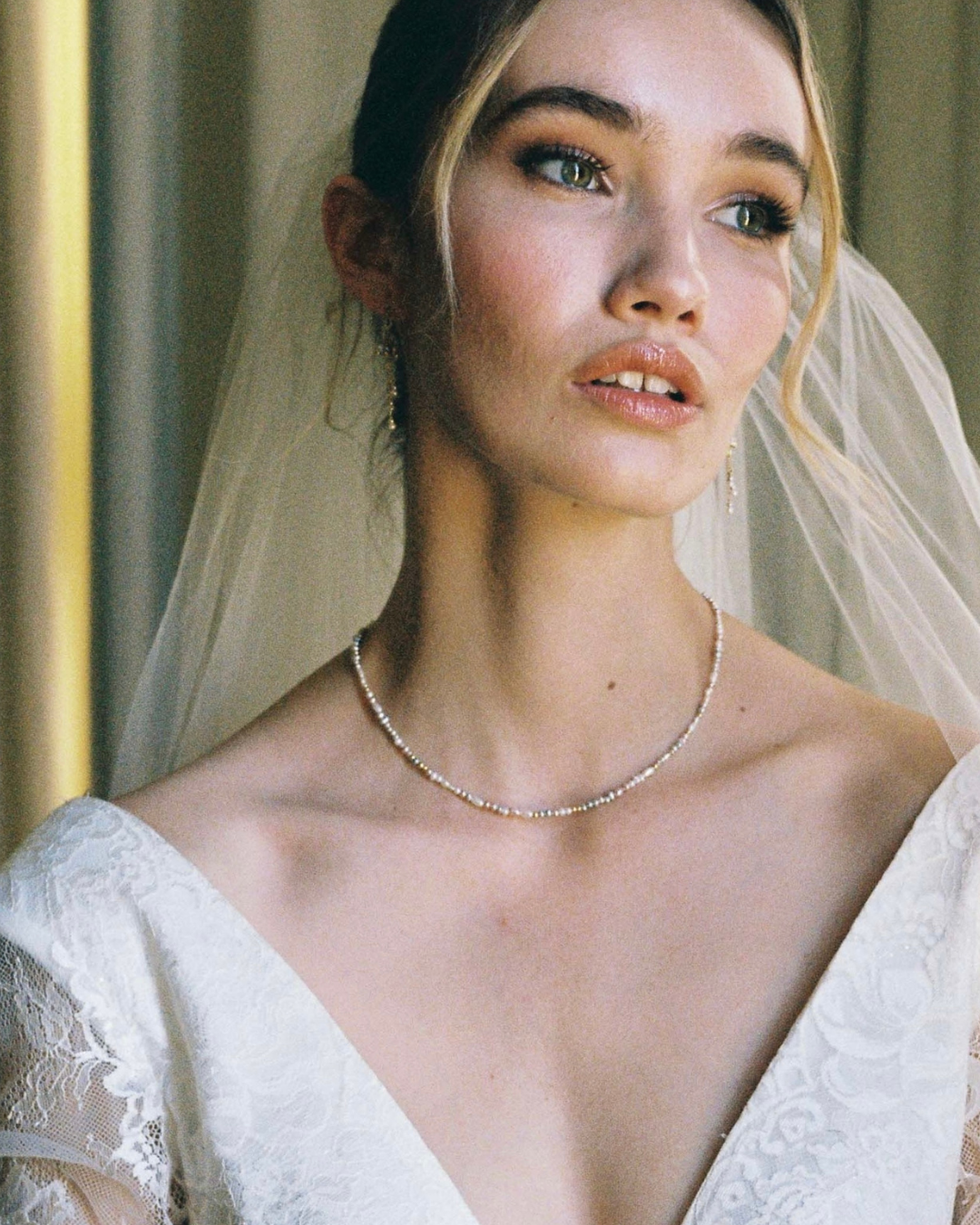 Bride wearing a white wedding dress with a veil and necklace.