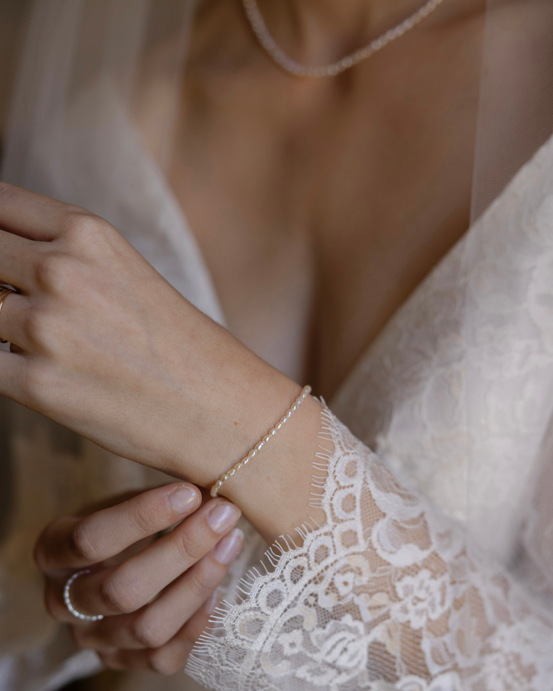 Close-up of a bride wearing a delicate bracelet with a blurred background