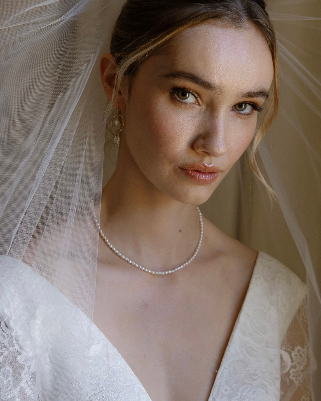 Bride wearing a pearl necklace and earrings with a soft background