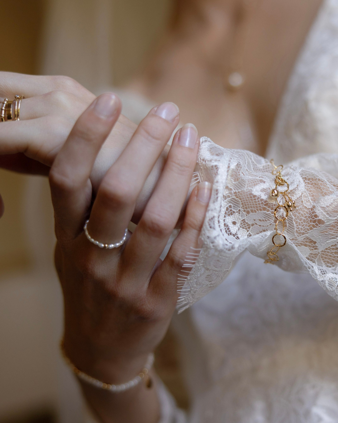 Close-up of a hand wearing a gold and pearl ring with a blurred background