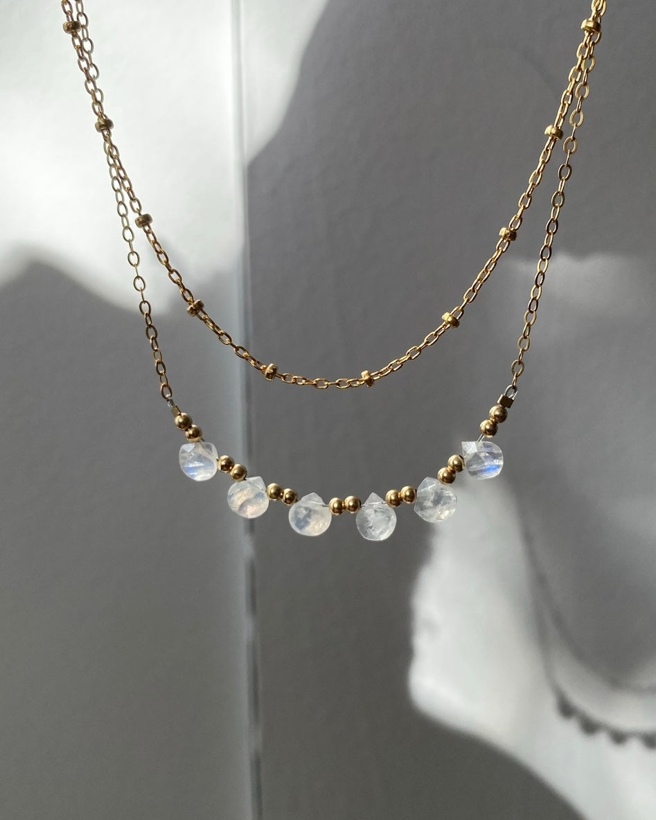 Ball chain choker necklace with a necklace with gold chain and moonstone gemstones beads on a neutral background