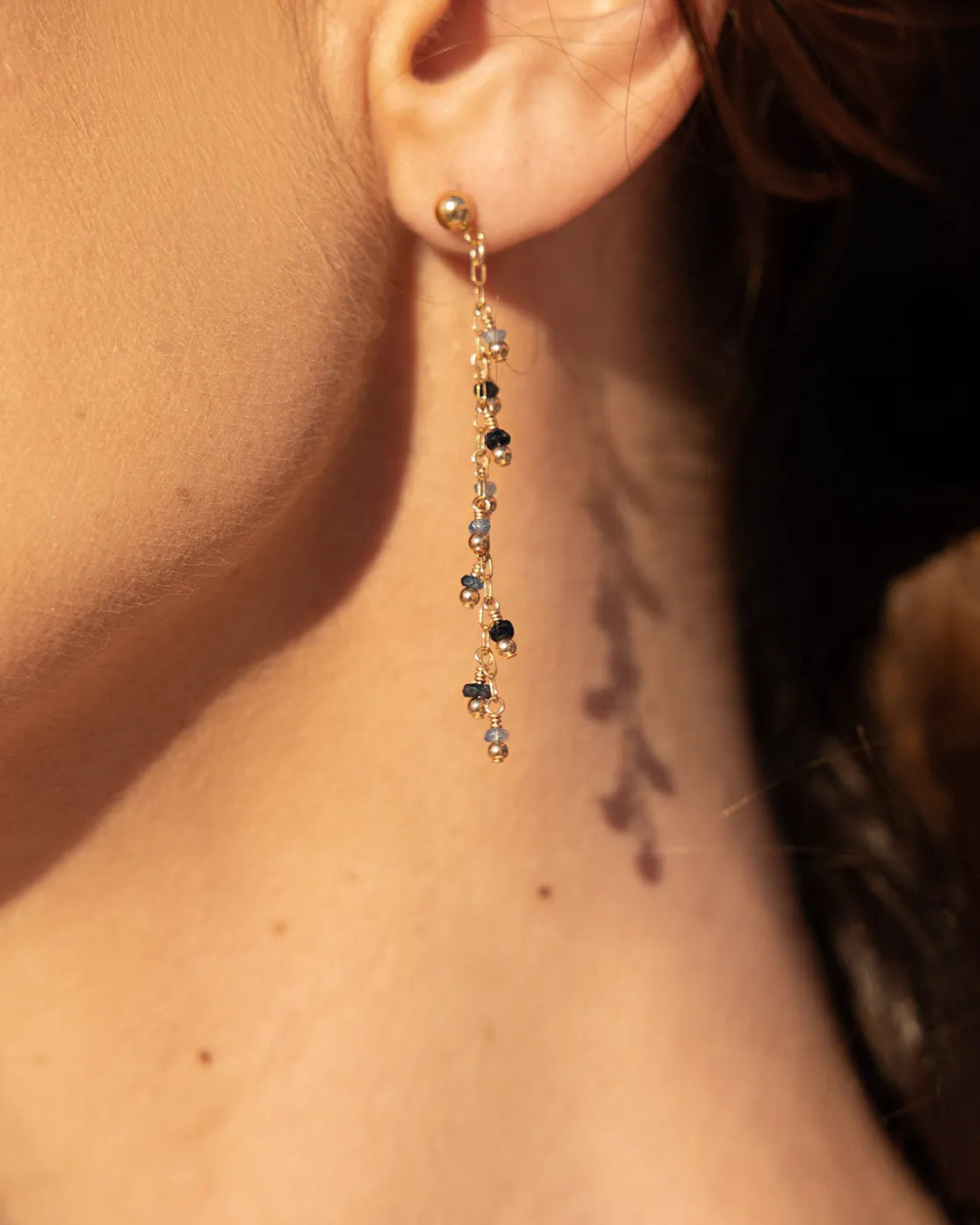 Close-up of a drop earring with sapphires and gold-filled accent beads