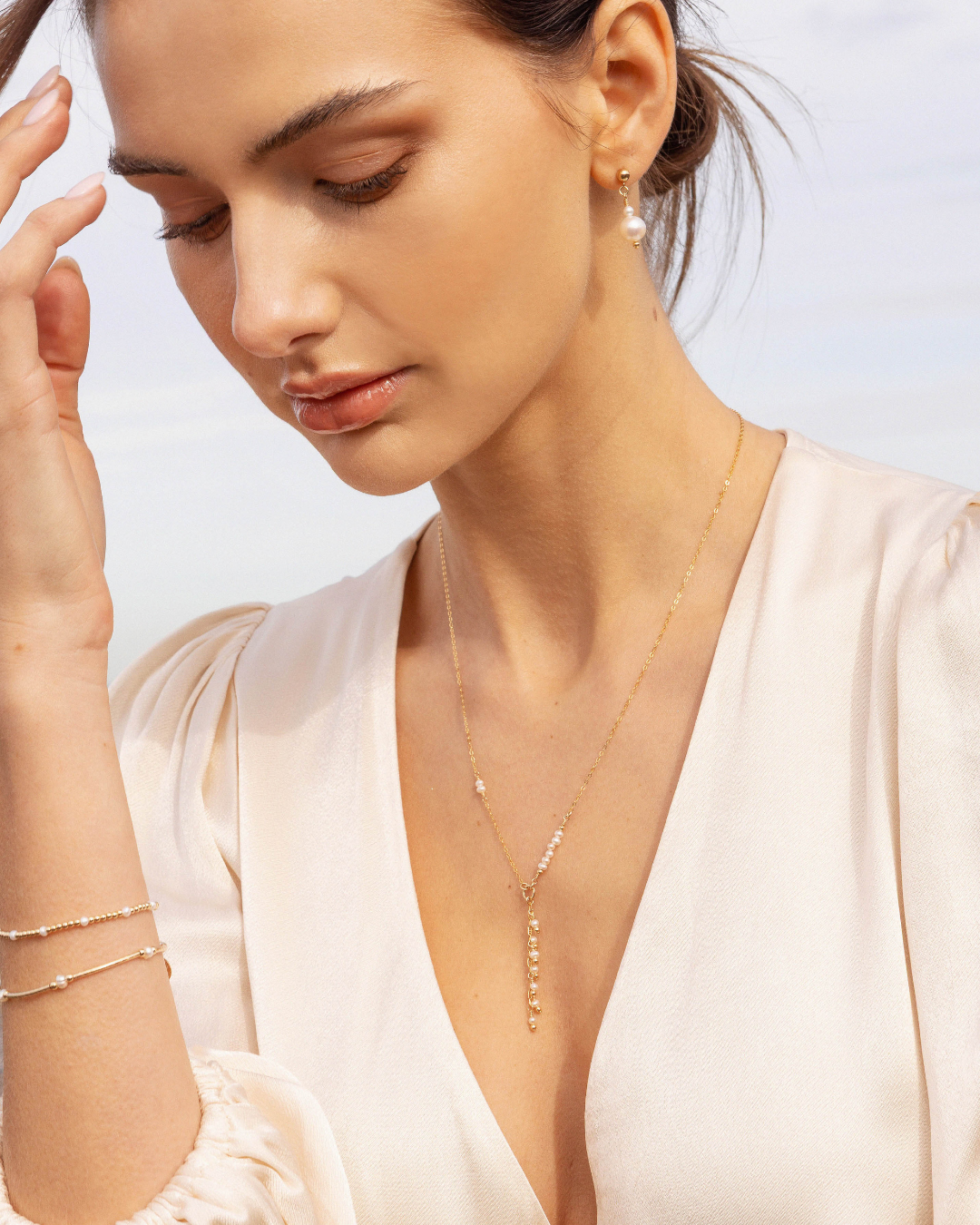 Woman wearing a delicate gold necklace with a soft background