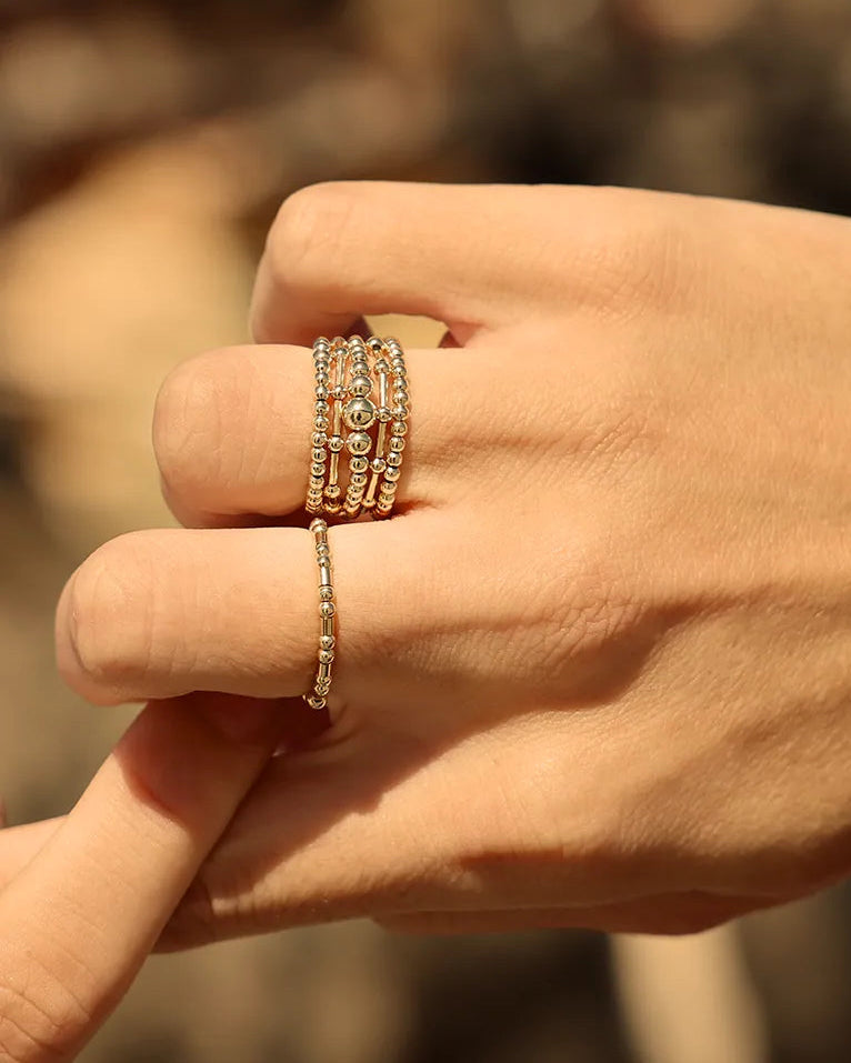 The Codie ring features an alternating pattern of round and tube gold beads, hand-threaded onto durable stretch cord.
