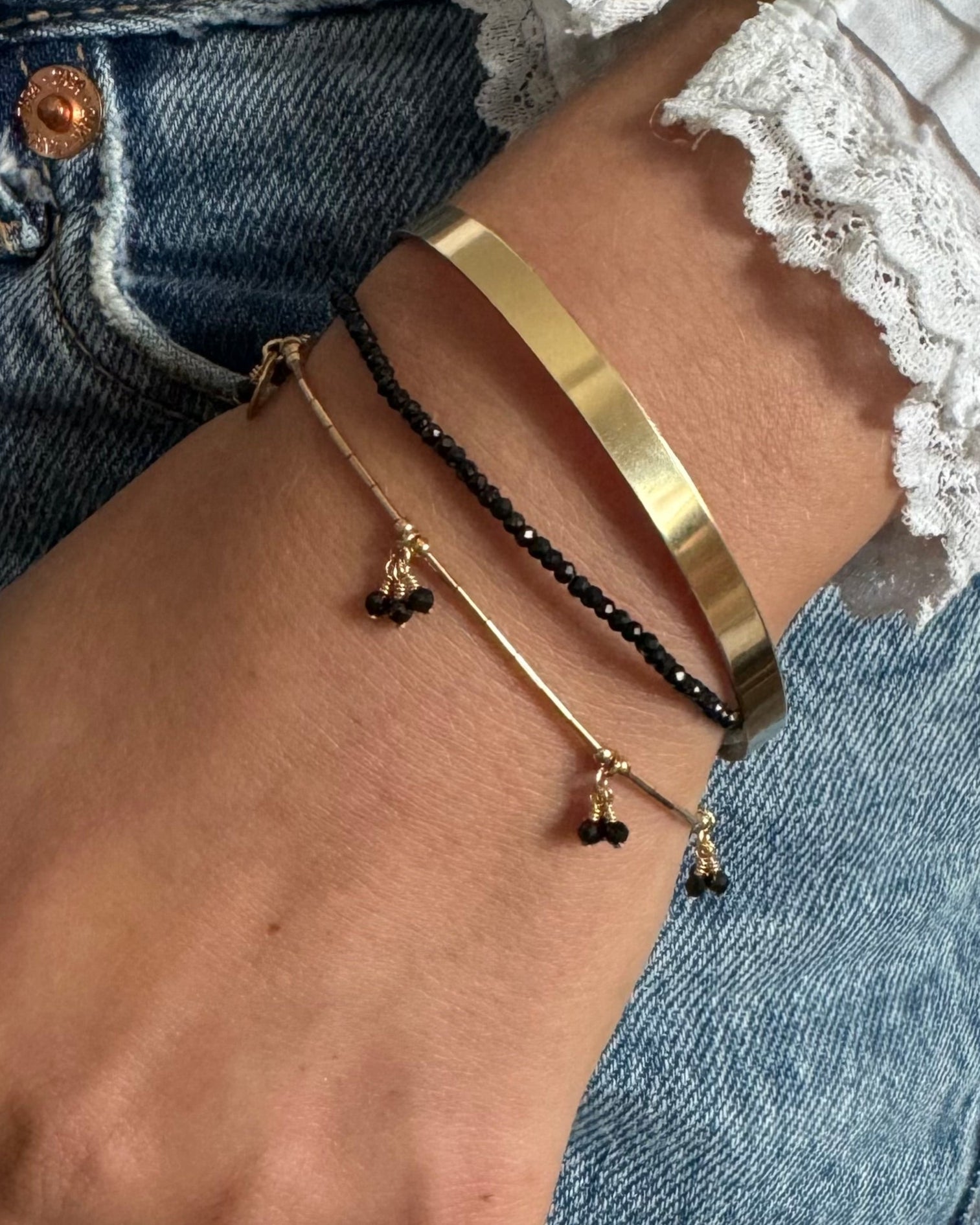 Close-up of a hand wearing gold bracelets with a blurred background