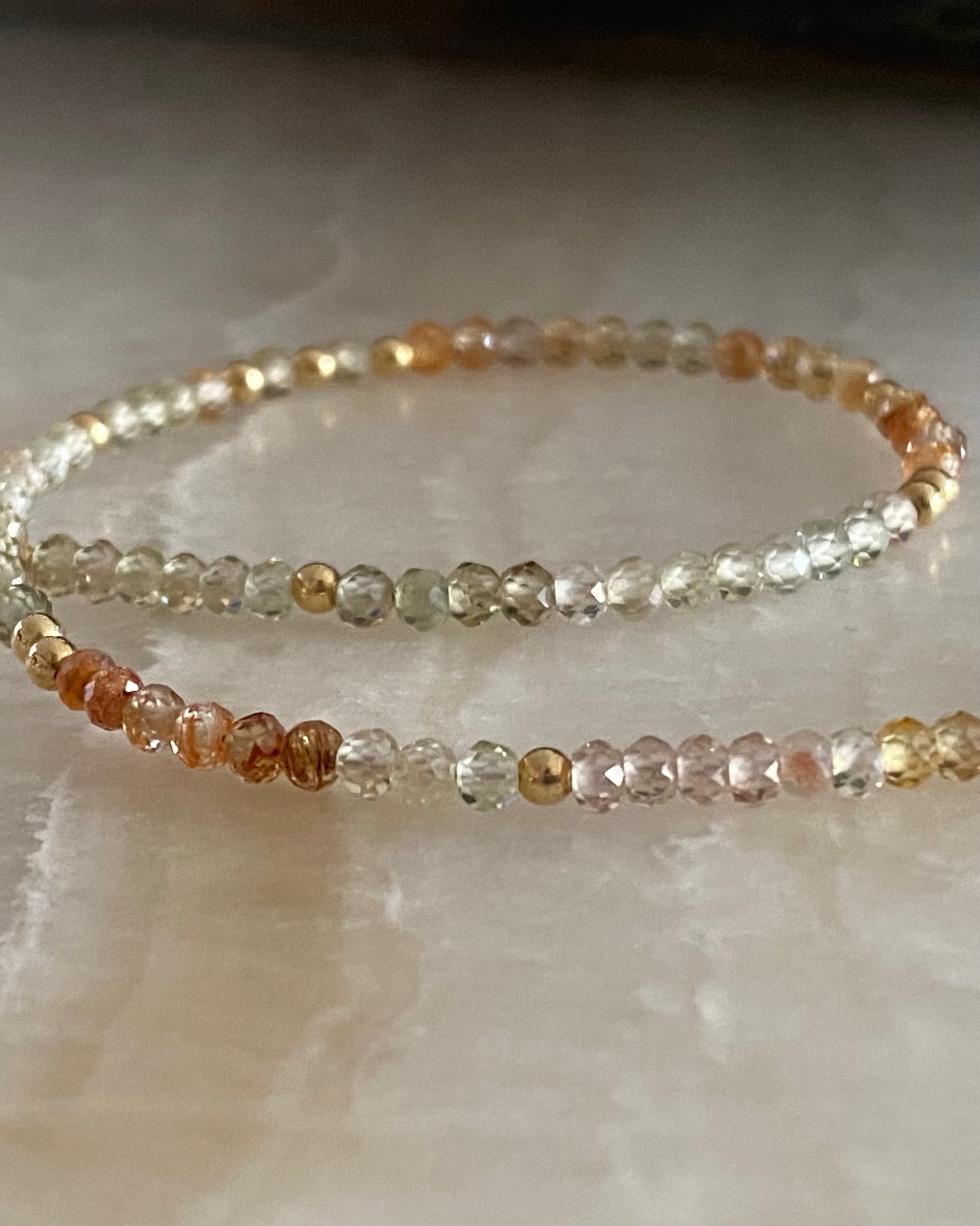 Gold and zircon gemstone necklace on marble background.