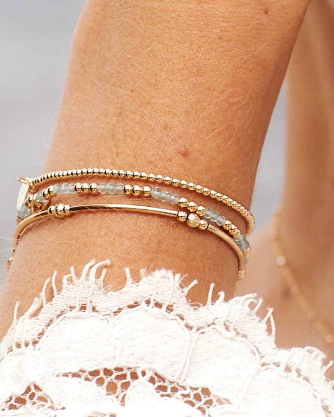 Gold bracelets on a wrist with a blurred background
