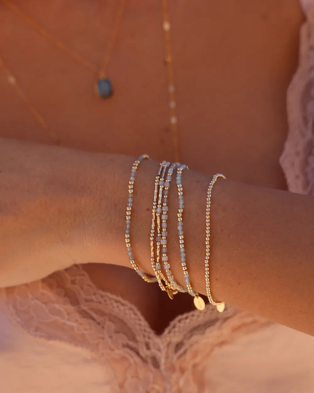 Model wearing bracelet with Apatite gemstones and gold beads hand threaded on durable stretch cord