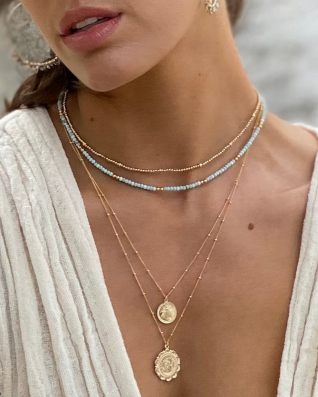 Close-up of a woman wearing layered necklaces with a blurred background