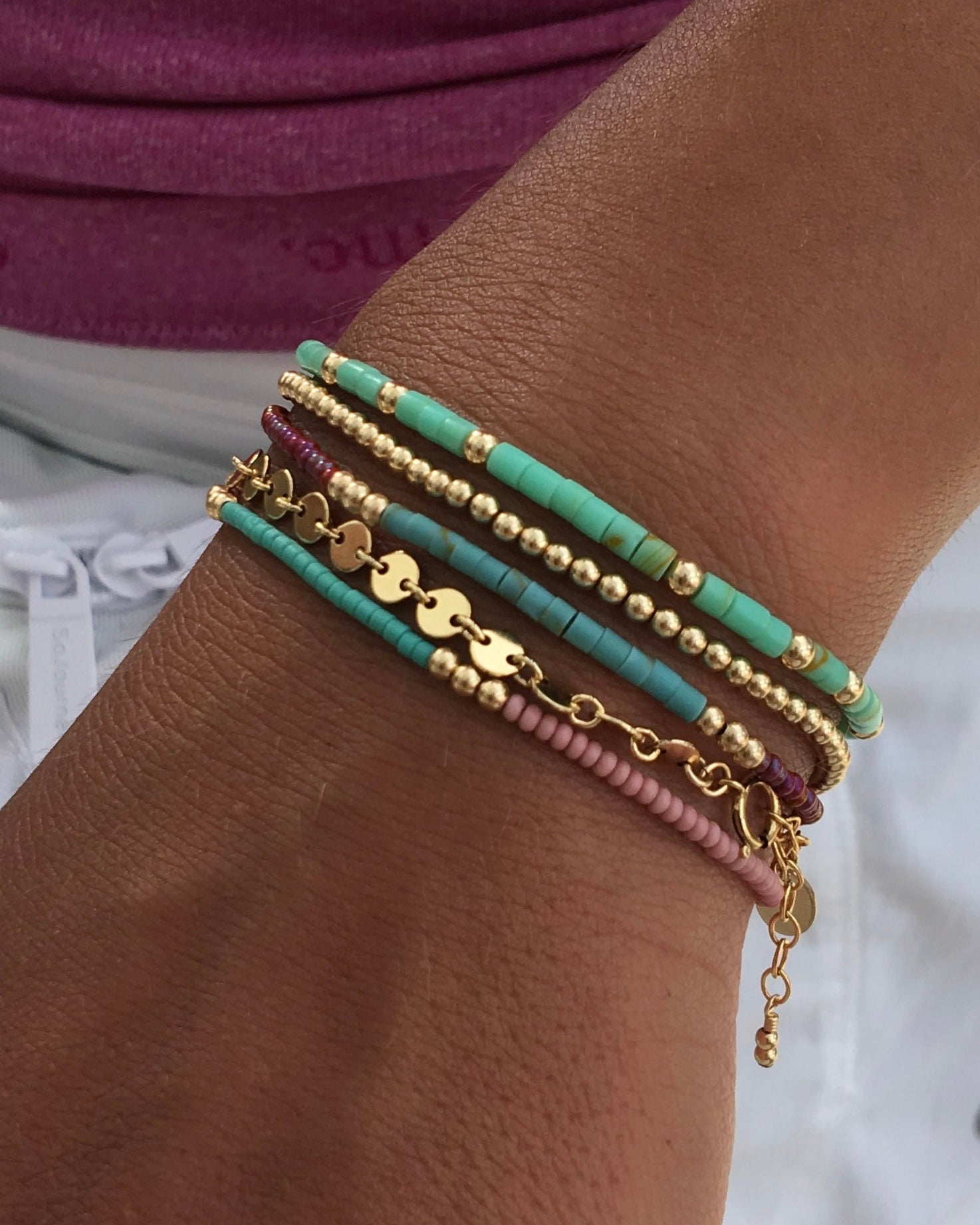 Close-up of a wrist wearing multiple colorful bracelets on a blurred background
