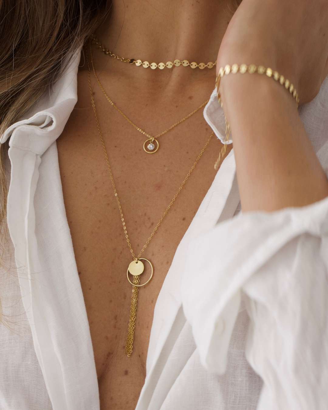 Gold necklaces and bracelet on a person wearing a white shirt