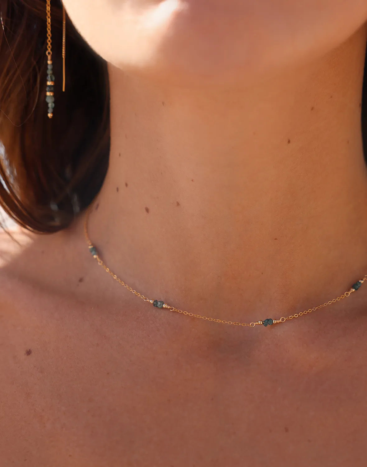 Model wearing Gold necklace wth blue raw diamond gemstones, paired with gold beads.