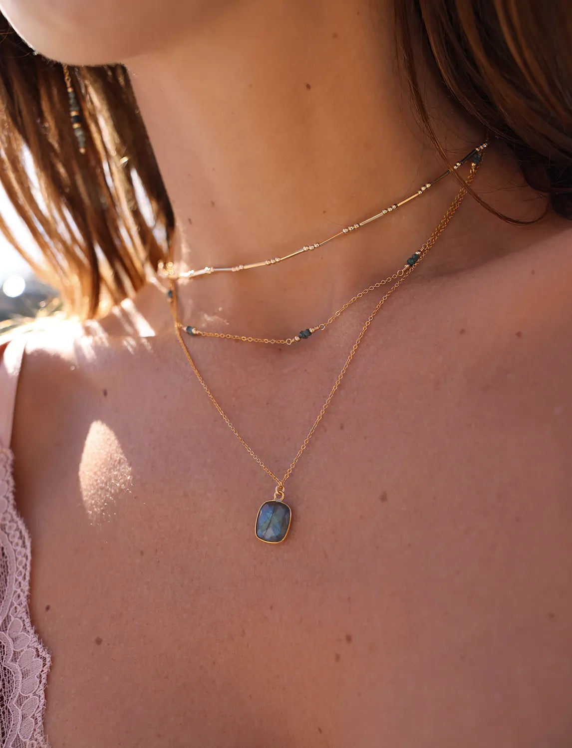 Model wearing Gold necklace wth blue raw diamond gemstones, paired with gold beads.